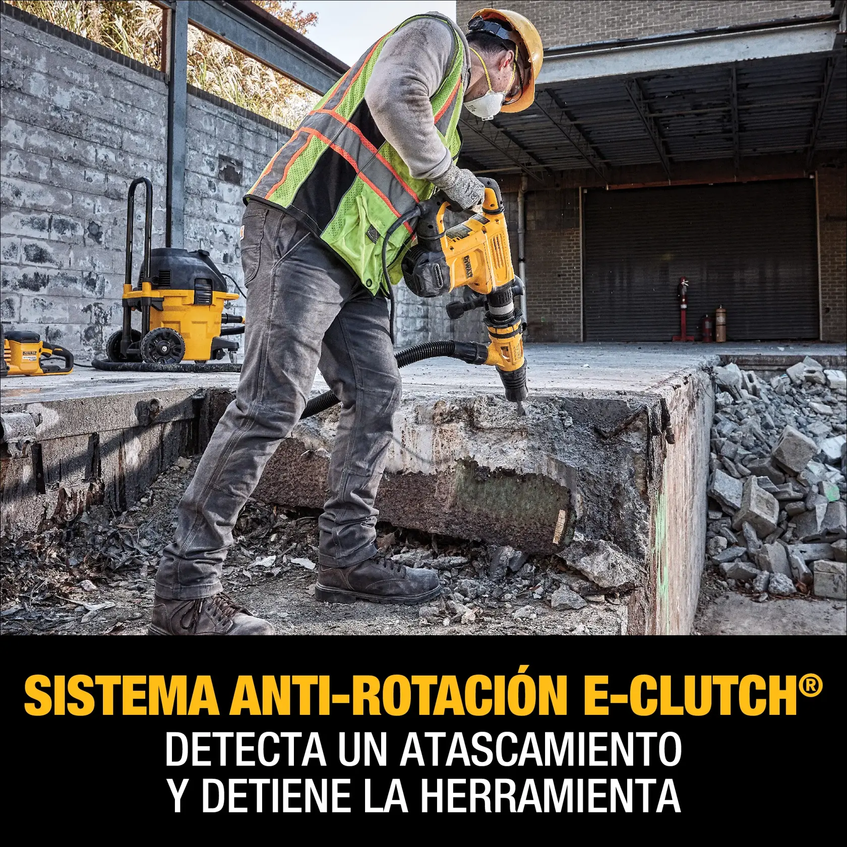 A construction worker in safety gear uses a yellow DEWALT rotary hammer tool to break up concrete. The worker is wearing a helmet, high-visibility vest, gloves, and a mask. A DEWALT vacuum and other equipment are visible in the background. The image promotes the anti-rotation E-Clutch system, which detects jams and stops the tool.
