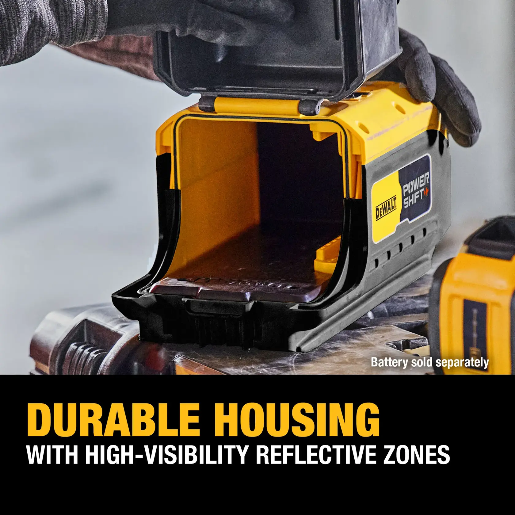 A close-up of a DEWALT Power Shift device with an open, durable yellow and black housing. The device features high-visibility reflective zones. A gloved hand is opening the compartment, and the text on the image highlights the durable housing and high-visibility reflective zones. Battery is sold separately.