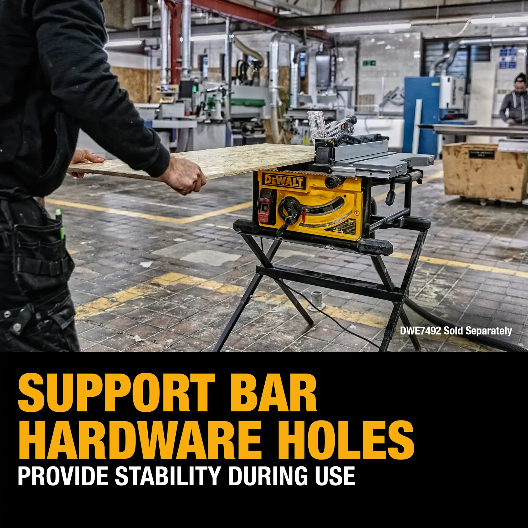 A DEWALT table saw is shown mounted on a stand in a workshop. A person is holding a wooden board and preparing to cut it using the saw. The image features text promoting the support bar hardware holes for stability during use, and notes that the DWE7492 accessory is sold separately.