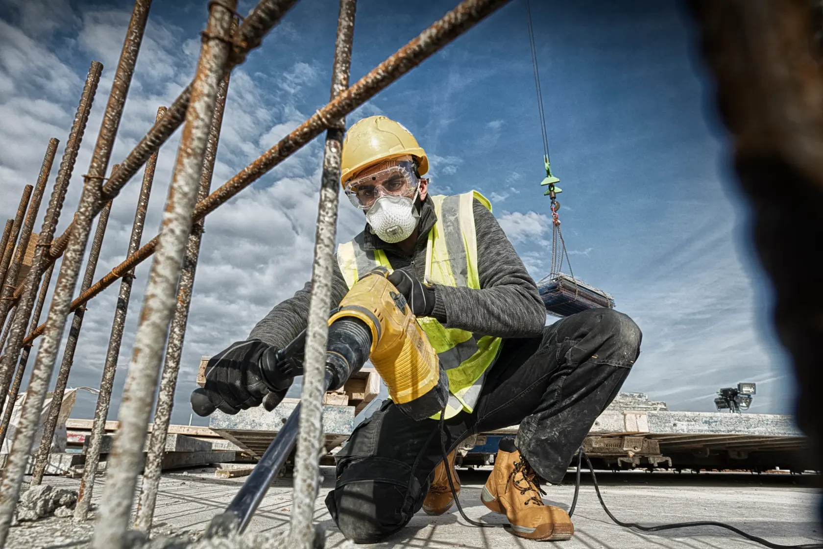 DEWALT D25481K, D25481 rotary hammer in use at construction site; worker drills concrete among rebars.