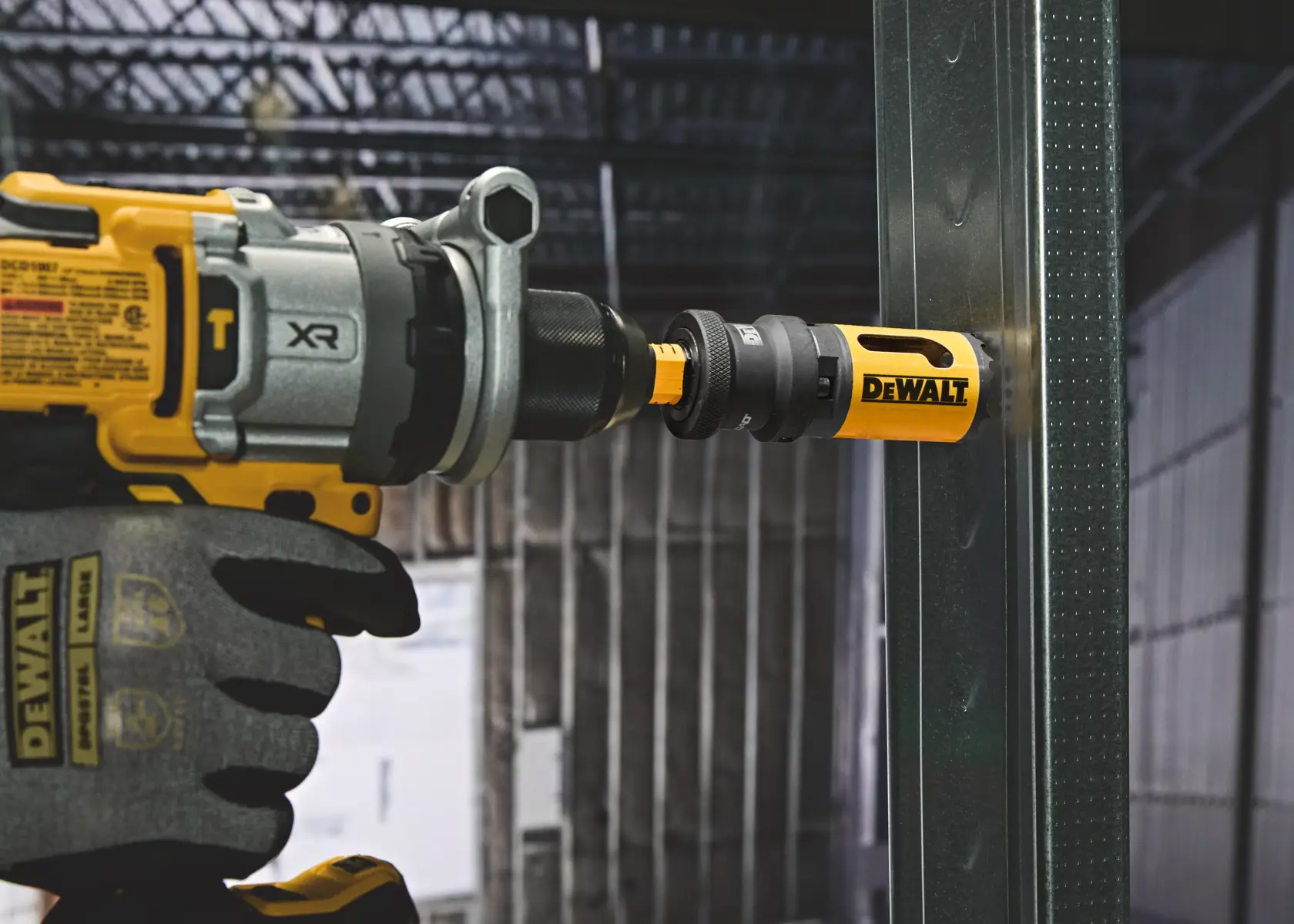 DEWALT power drill with hole saw attachment cutting through metal beam in industrial setting.