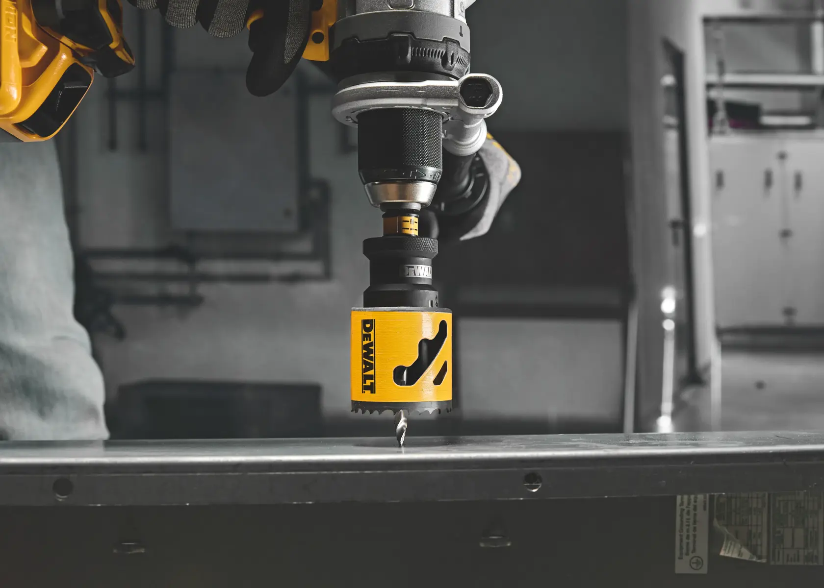 DEWALT hole saw attached to drill, cutting through metal surface in a workshop setting.