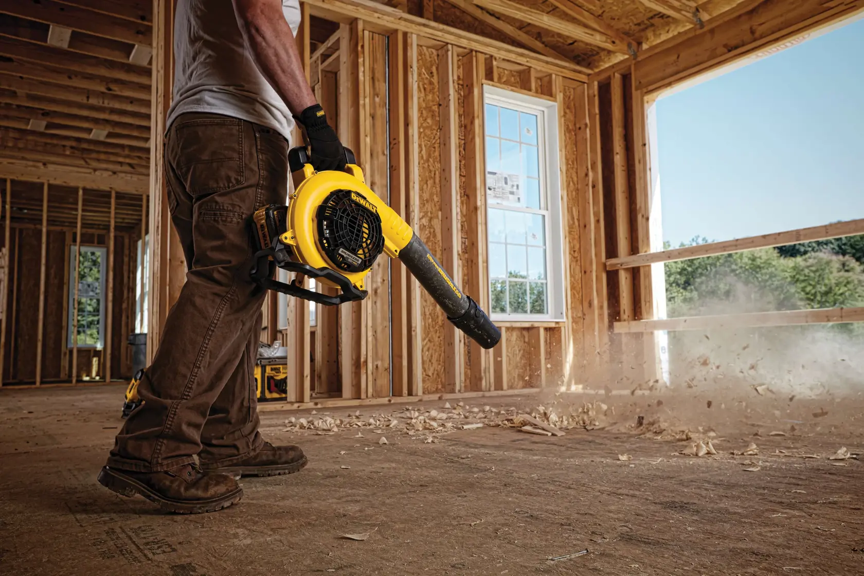 FLEXVOLT Handheld Blower being used by a worker to clear heavy jobsite debris on a rooftop