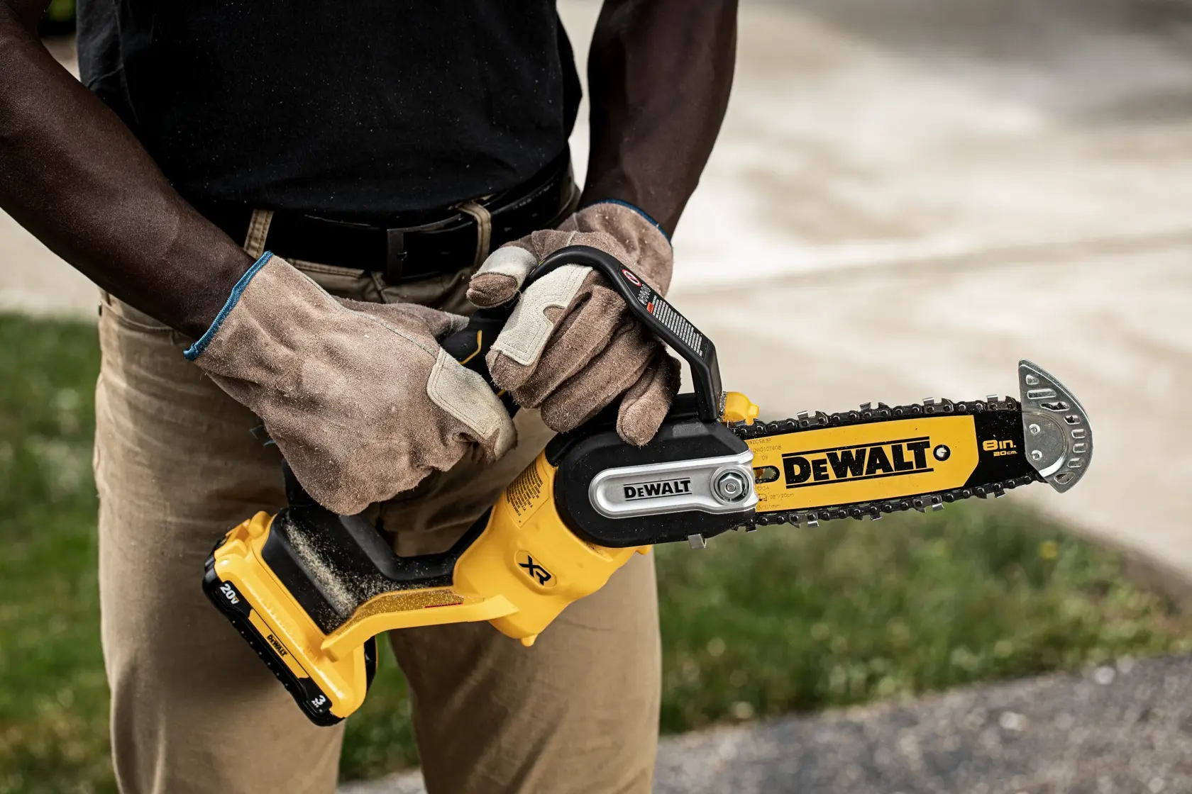 Man holding the DEWALT Pruning Chainsaw with 3 AH battery in close up
