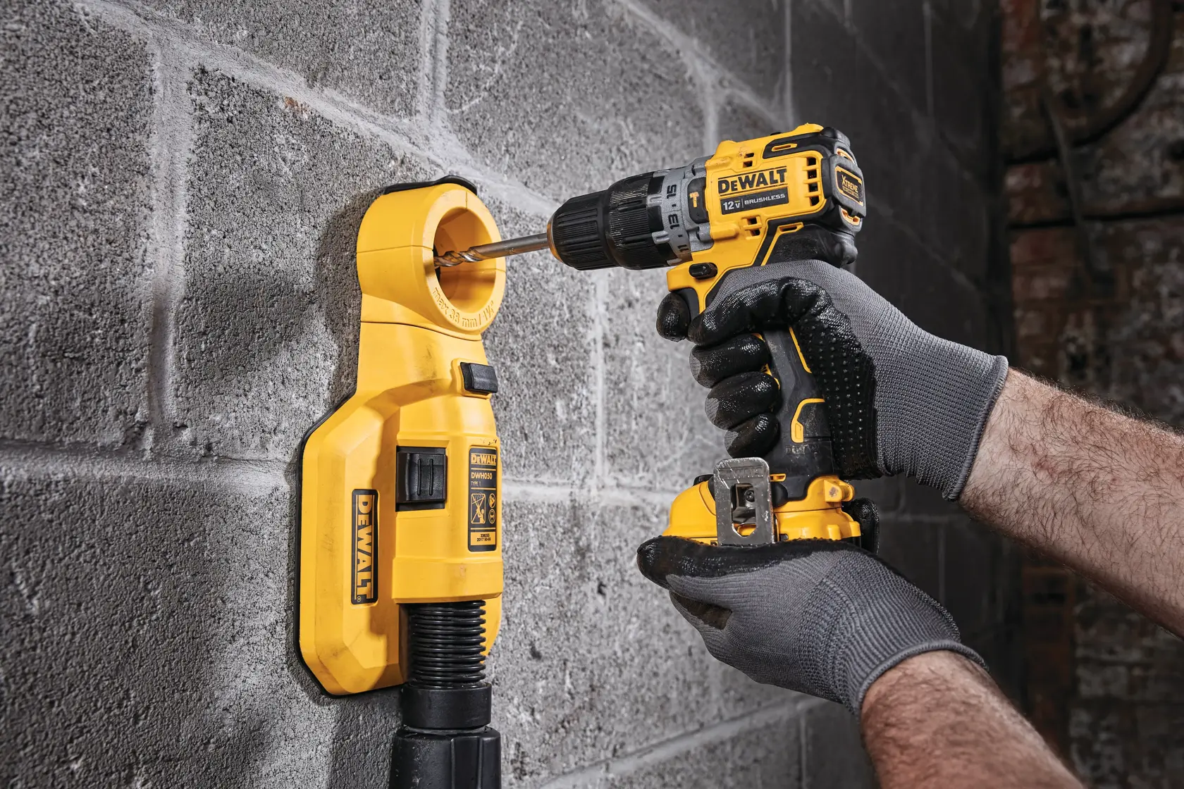 A person wearing safety equipment uses a DEWALT cordless drill to work on a concrete wall. The individual’s face is blurred for privacy.
