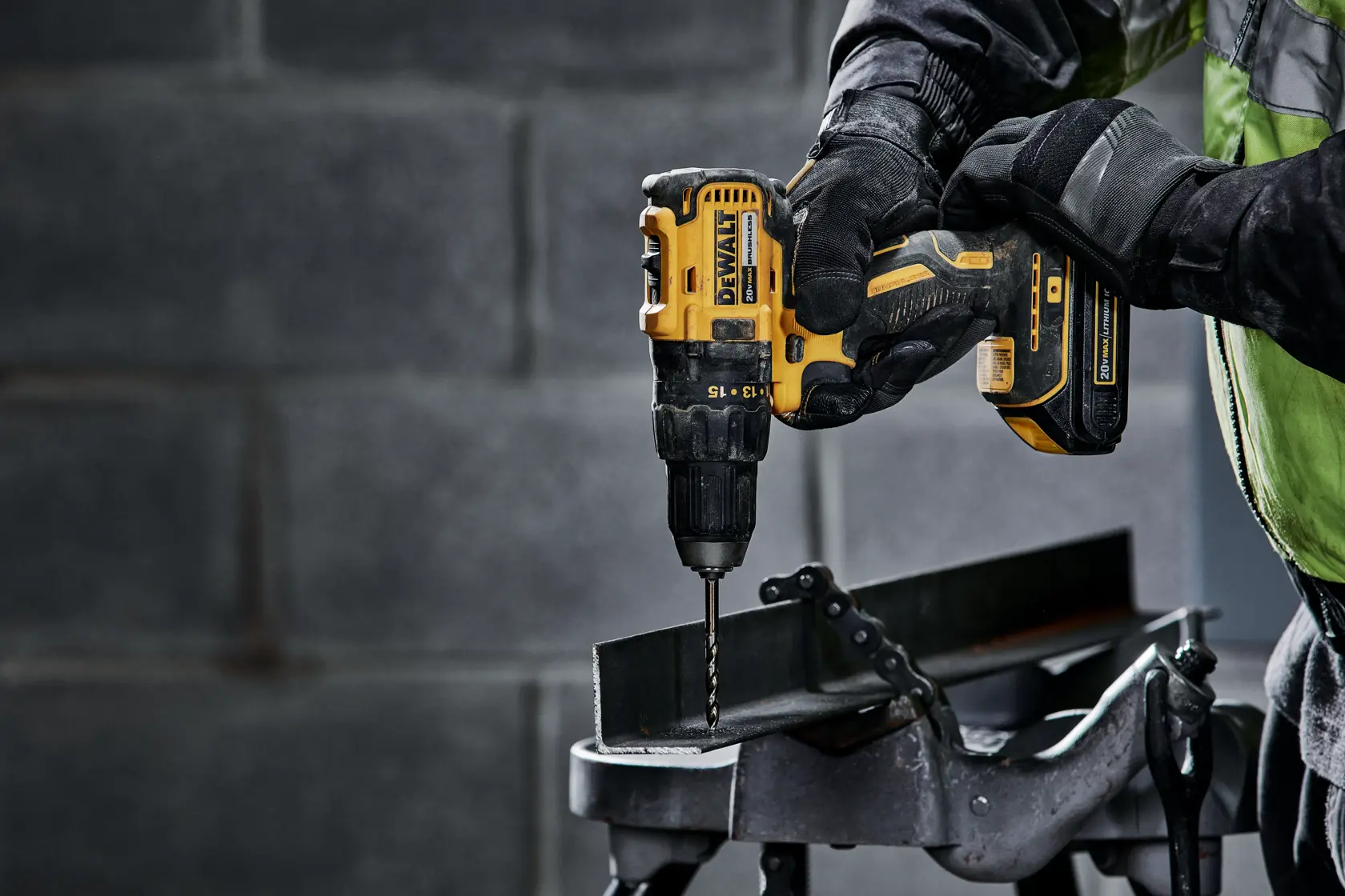 DEWALT Impact Driver powered by a 20V 2Ah battery, using it downward by a man with gloves on a metallic electric box.