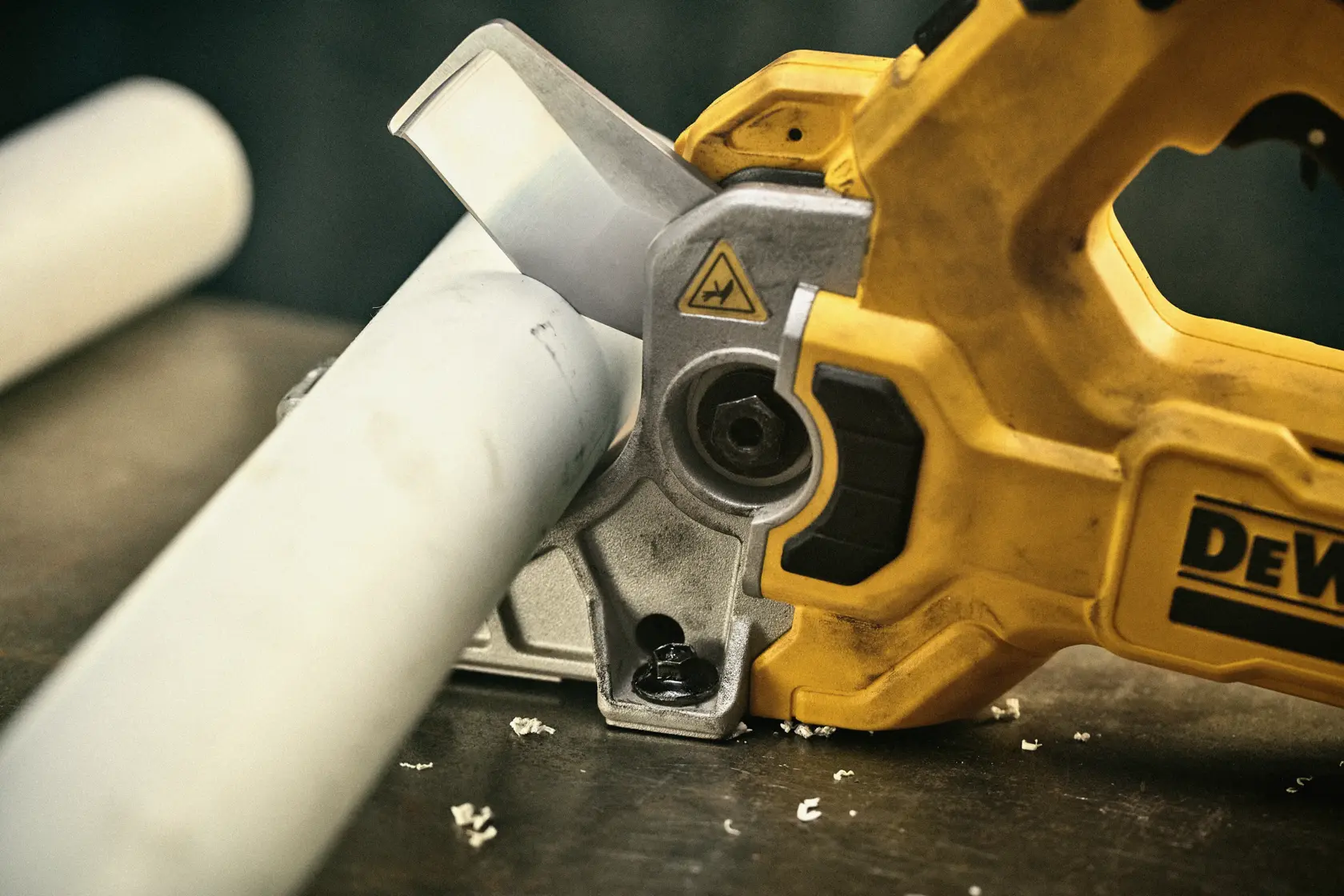 DEWALT Plastic Tubing Cutter mounted to work station cutting plastic pipe. 