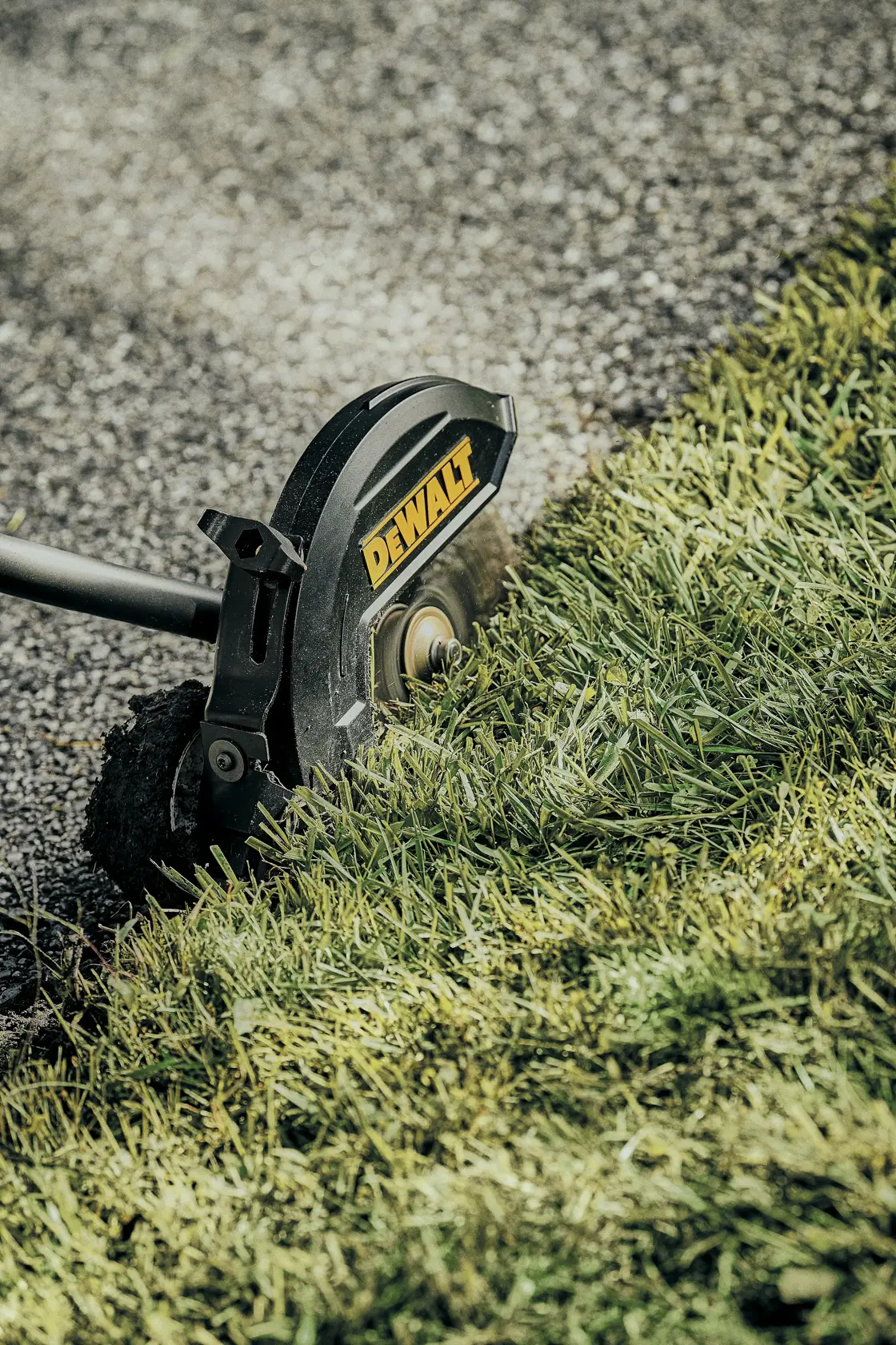 Ground-level view of brushless attachment capable edger kit cutting grass overgrowth.