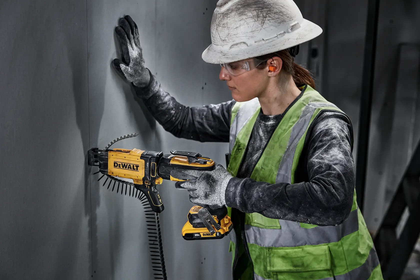 individual using a 20V MAX XR(®) Brushless Drywall Screwgun with collated attachment on a wall