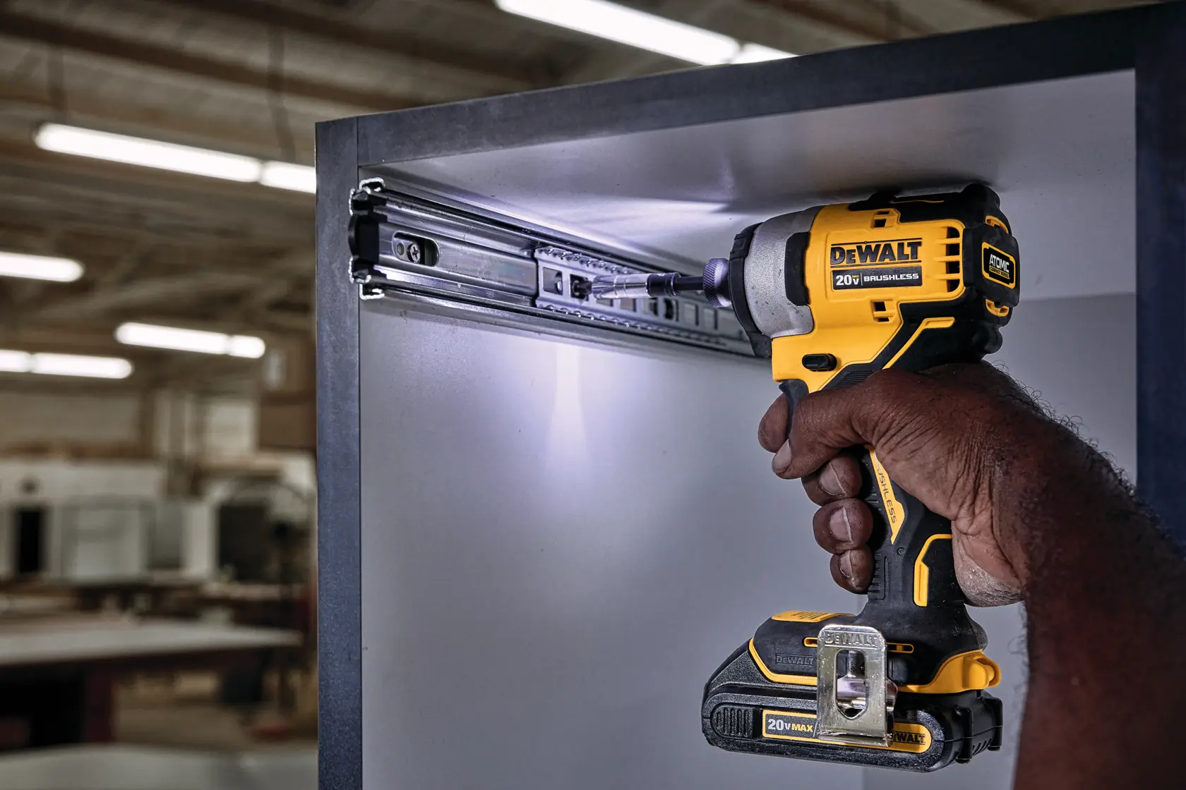 ATOMIC brushless cordless compact impact driver drilling through a metallic box.