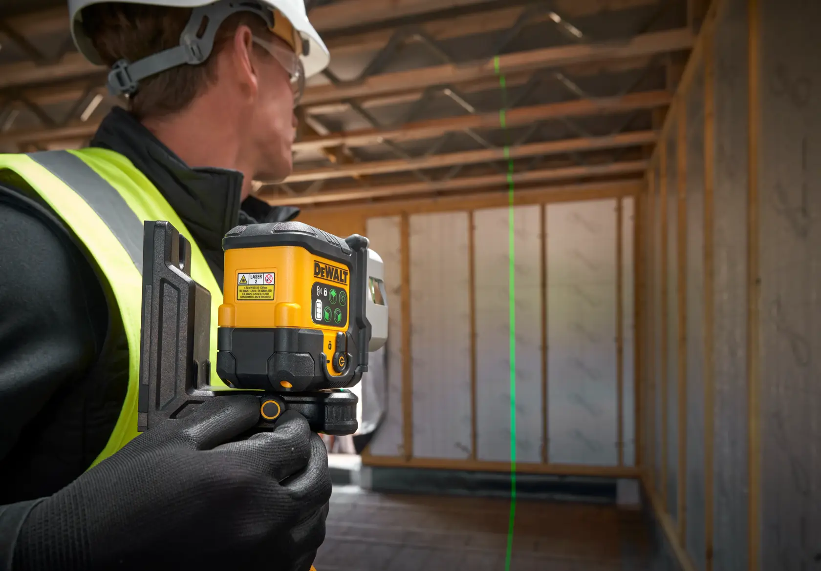 The DEWALT 3x 180 USB Green Beam Laser on tripod being set by worker on worksite.