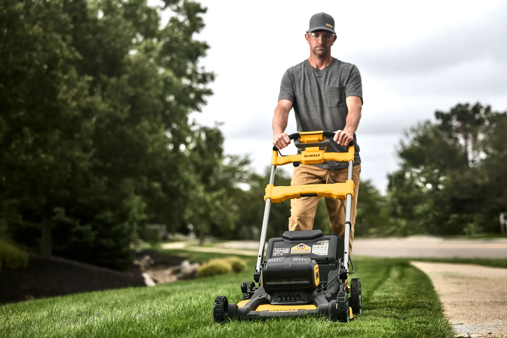 Close up side view of landscaper mowing tall grass using DEWALT 60V self propelled mower