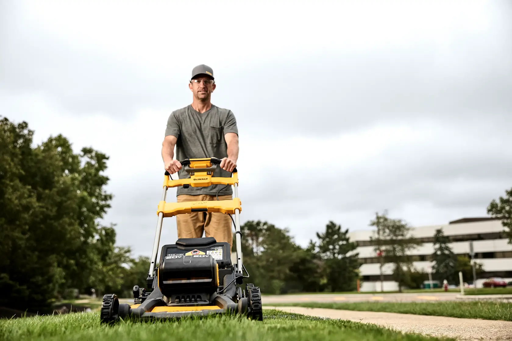 Close up 3/4 view of landscaper mowing tall grass using DEWALT 60V self propelled mower