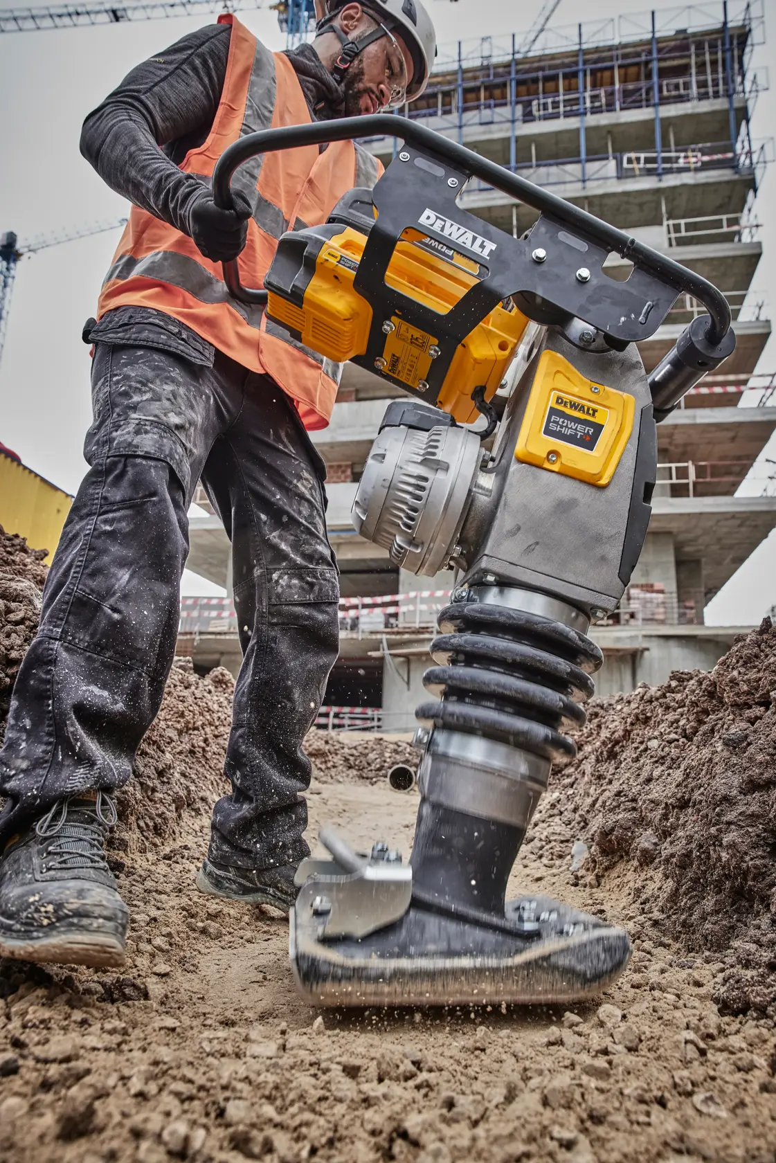 Man operating rammer in dirt trench