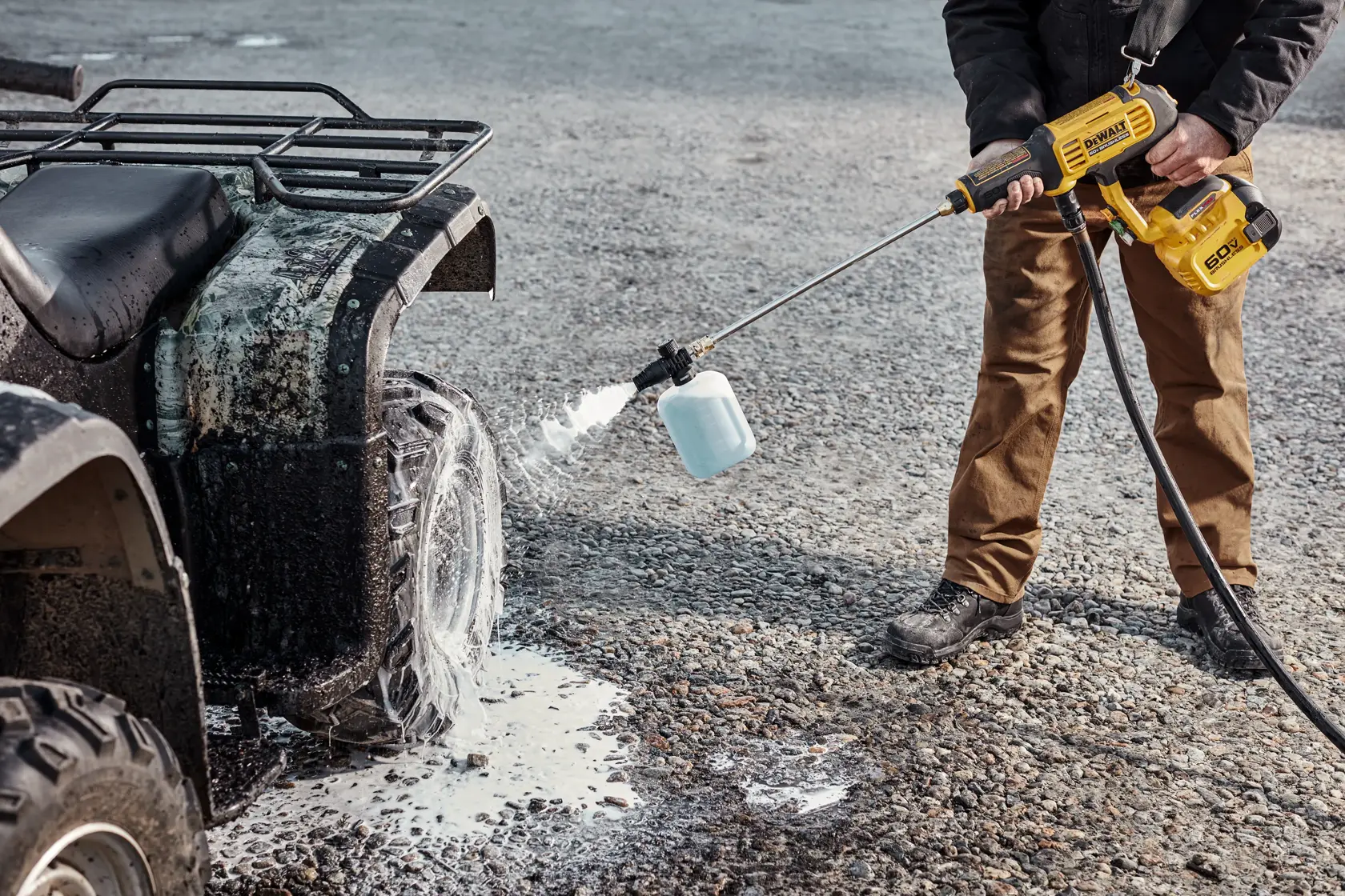 User cleaning dirty ATV tire with DEWALT 60V Power Cleaner