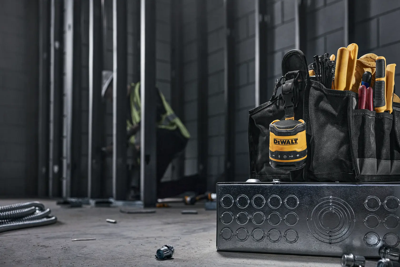 DEWALT mono speaker on a jobsite hooked onto a tool belt