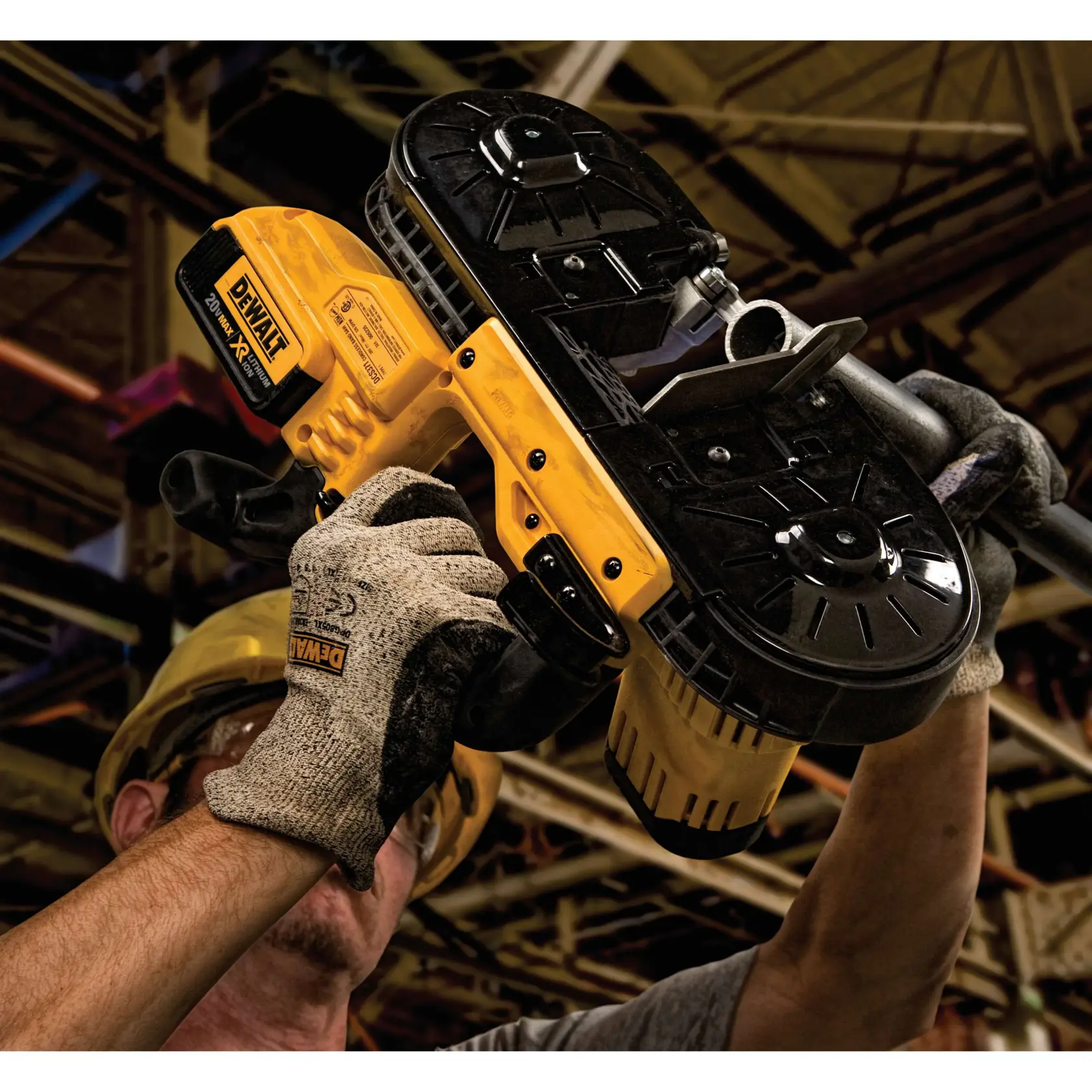 A person wearing gloves and safety gear uses a DEWALT cordless band saw to cut a metal pipe in an industrial setting.