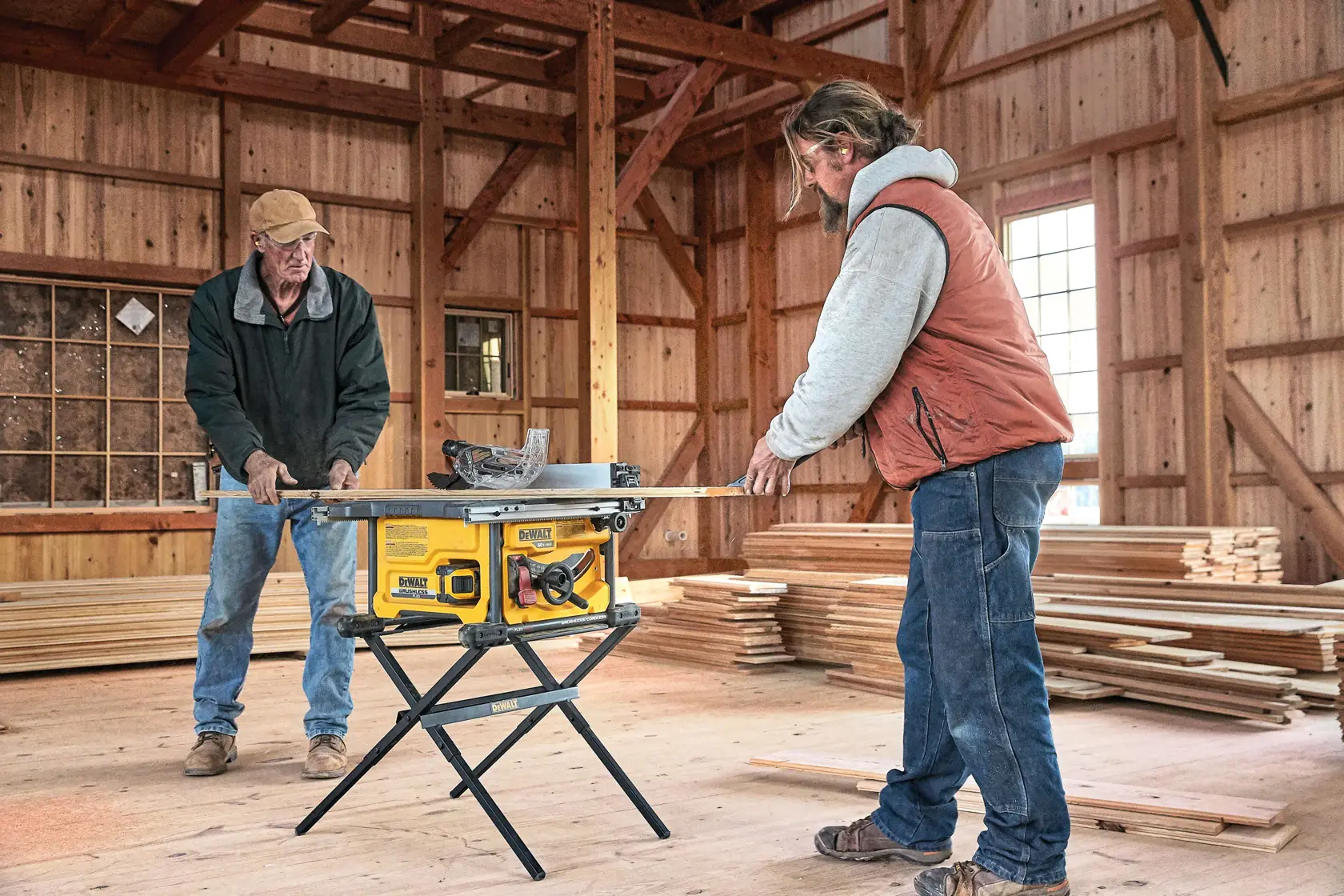 FLEXVOLT table saw being used by two people on wooden sheet.