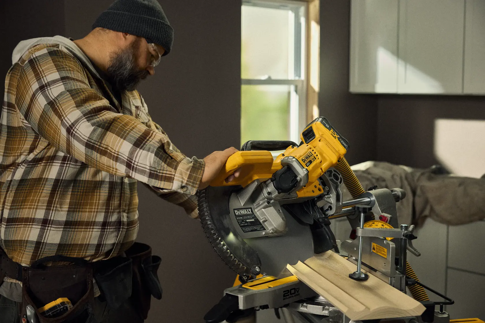 Talent cutting a piece of material with the 20V MAX* XR® 12in. Double Bevel Sliding Miter Saw Kit in a residential environment