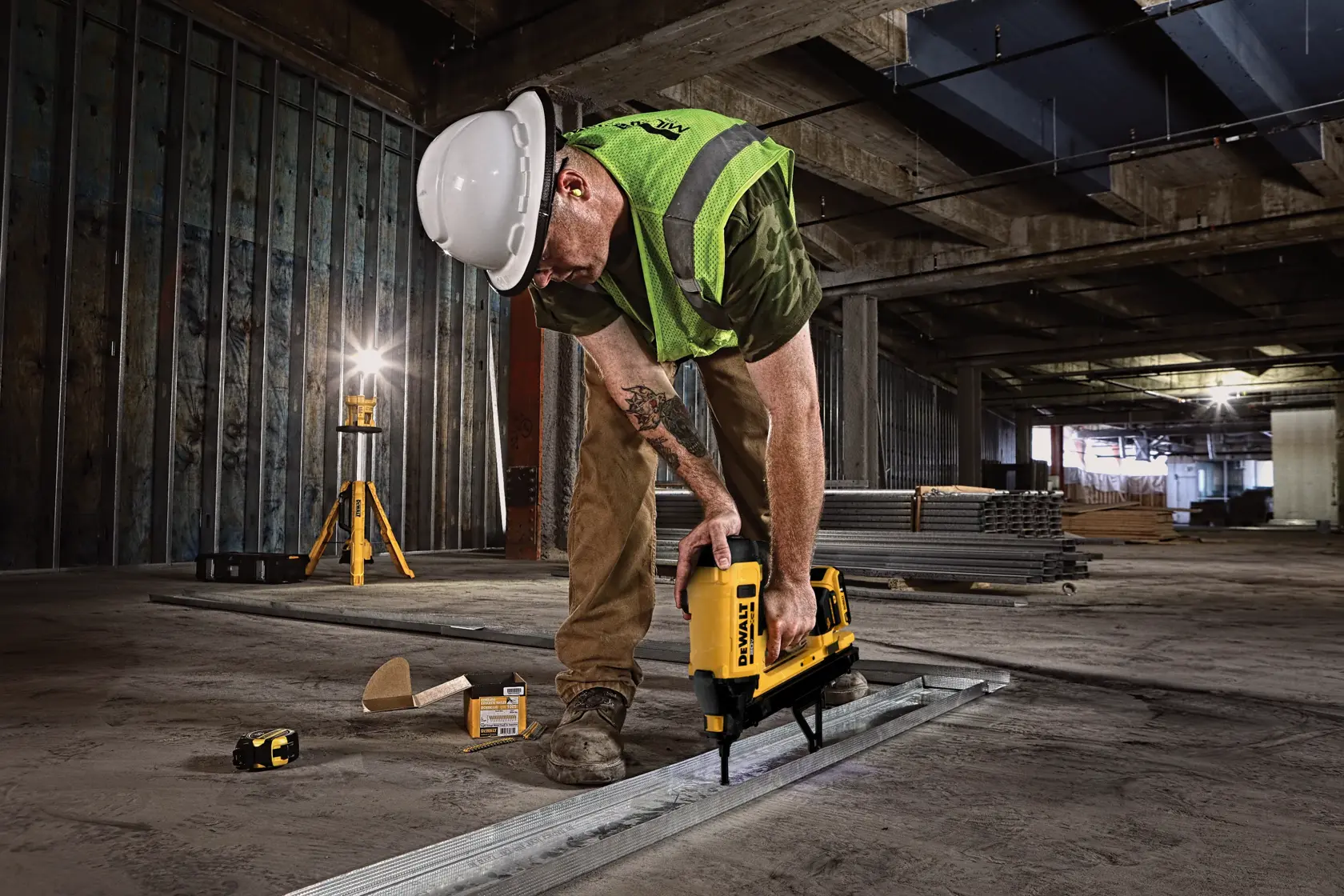 Worker uses DEWALT DGN845D1-QW and DGN845D1 tool on industrial floor, wearing safety gear. Photography product.