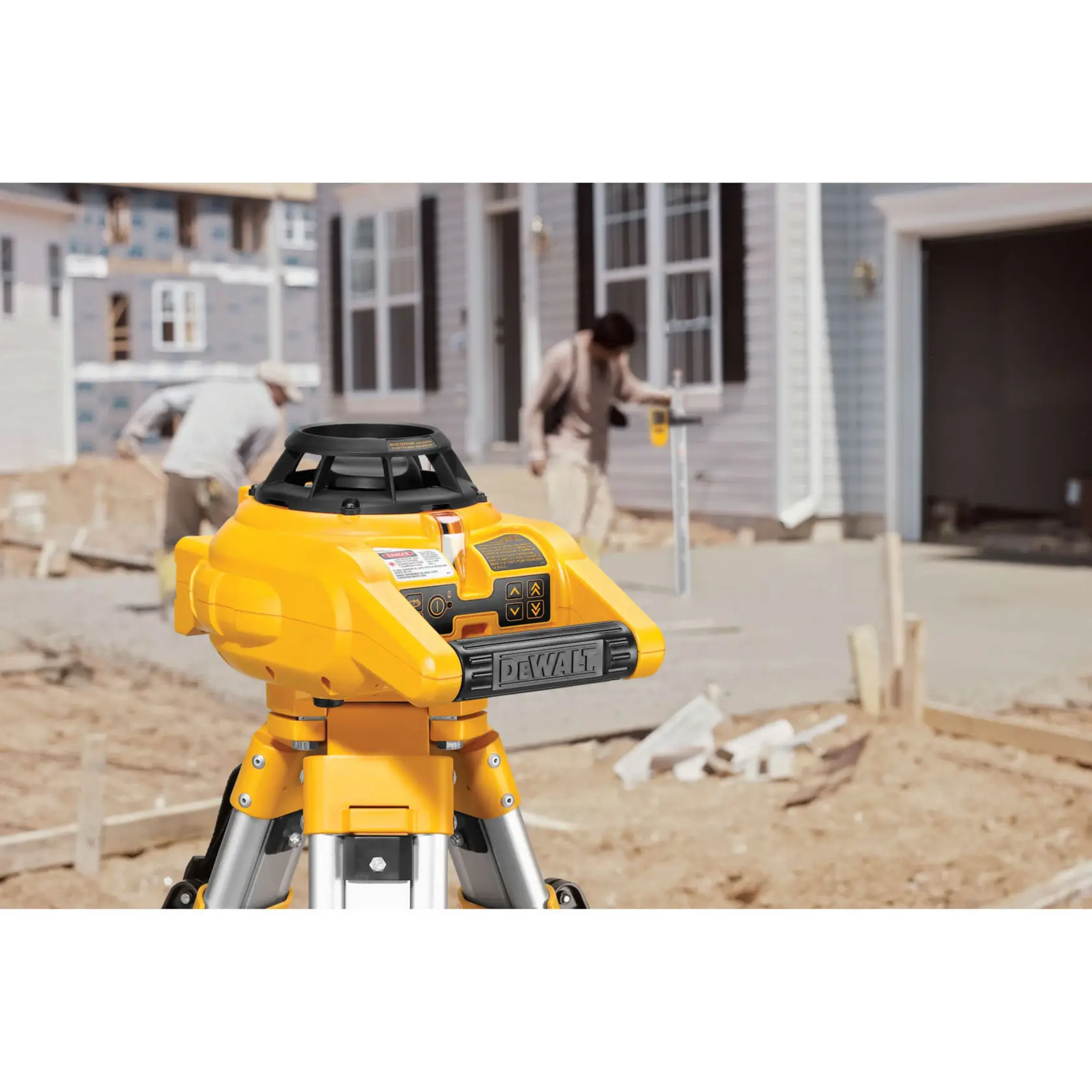 Interior and exterior rotary laser level kit mounted on a tripod at a construction site.