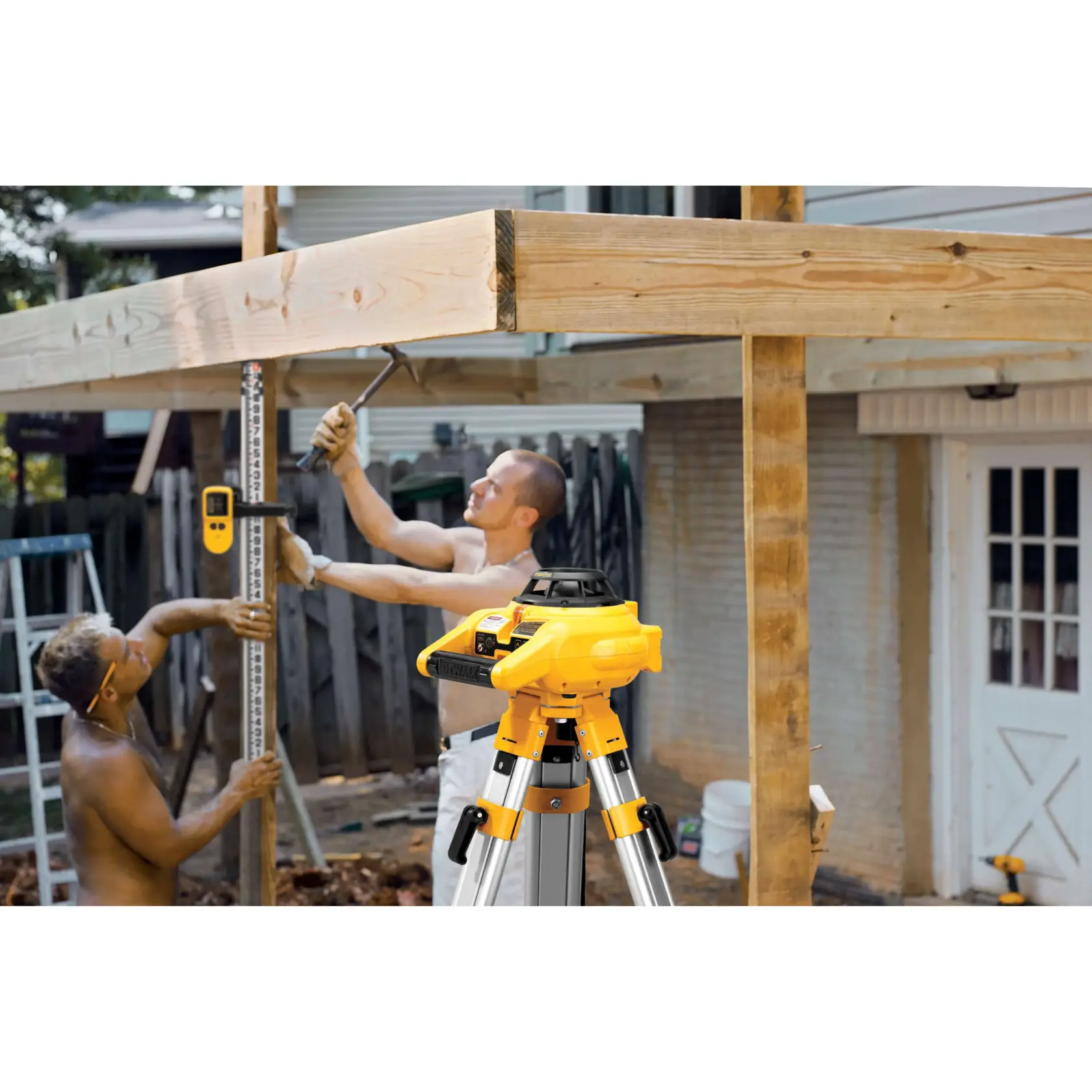 Interior and exterior rotary laser level kit mounted on a tripod and being used by construction workers.