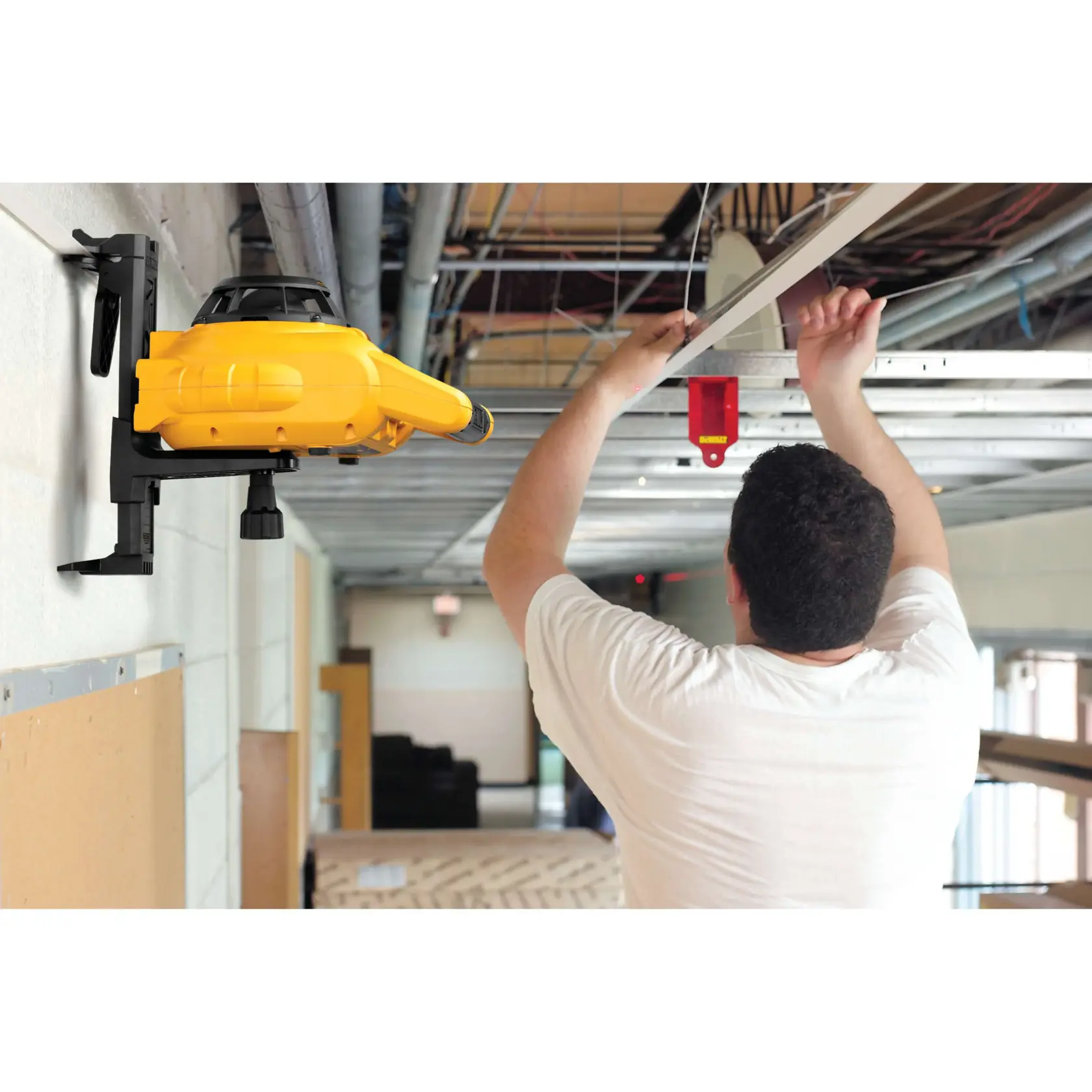 Interior and exterior rotary laser level kit attached to a wall and being used by a person.