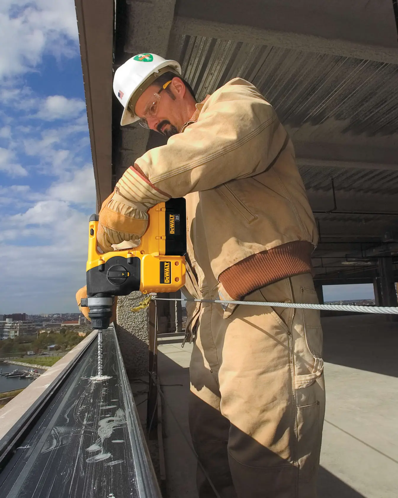 Three eighths inch by 4 inch by 6 and half inch S D S Plus Full Head Carbide Drill Bit being used by worker to drill into sill plate in wall opening.