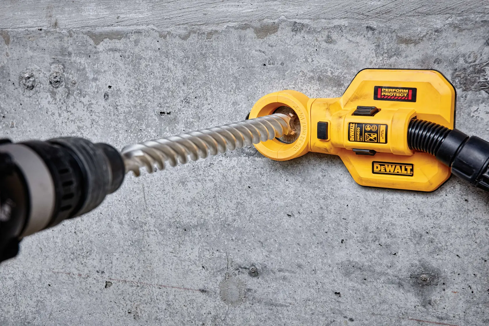 SDS Max High Impact Carbide 4 Cutter Drill Bit being used by worker to drill through concrete wall at outdoor work site.
