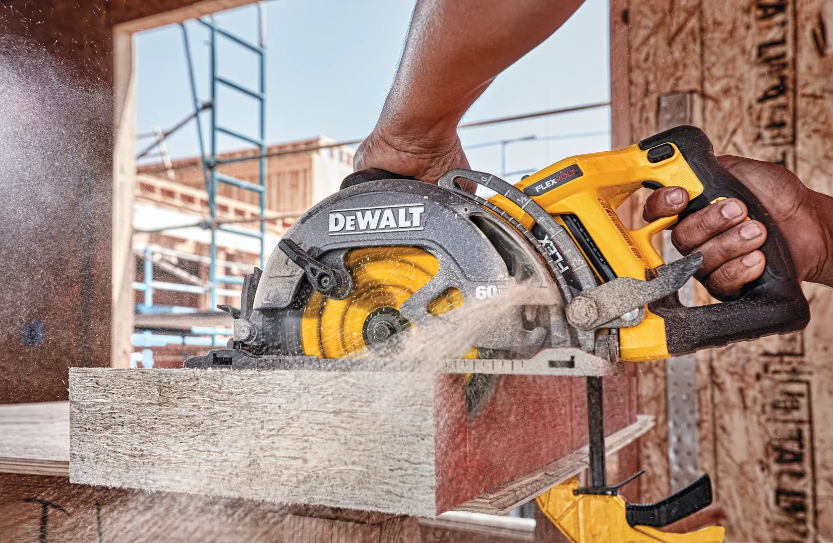 A DEWALT circular saw being used to cut a piece of wood at a construction site, with sawdust flying.