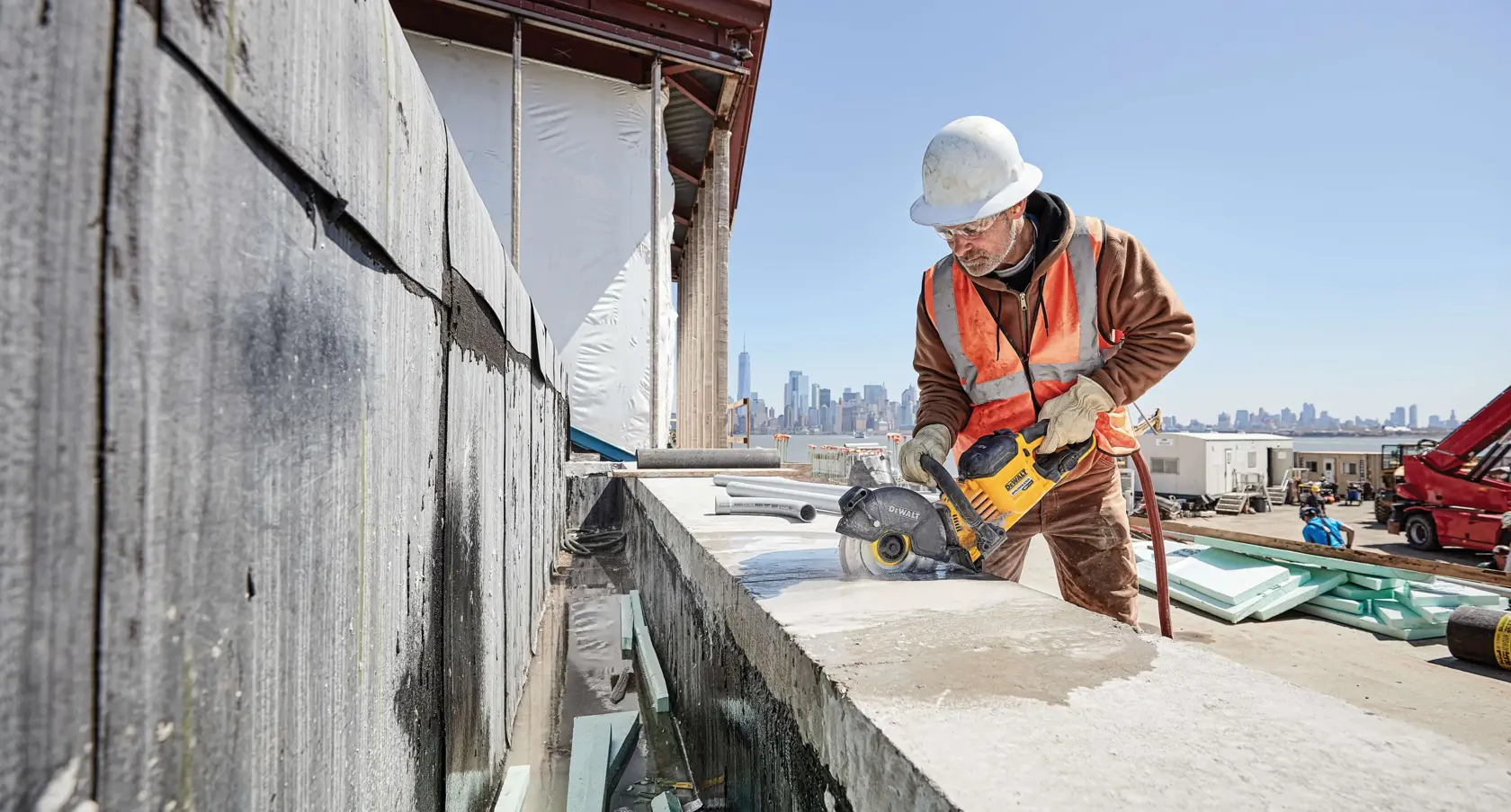 FLEXVOLT DIAMOND CUTTING WHEEL being used by worker to cut through concrete boundary wall at construction site.