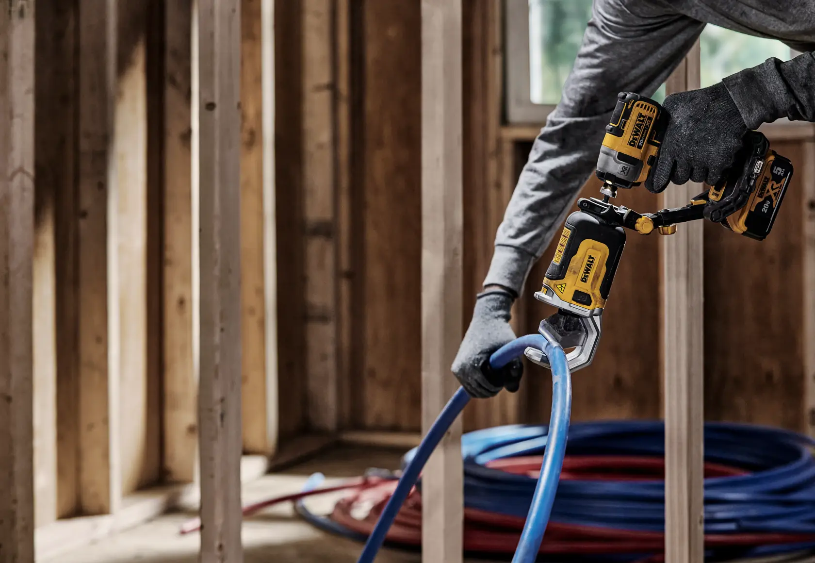End user using DEWALT IMPACT CONNECT PVC/Pex Cutter attachment on Impact Driver to cut pex tubing near wood framing