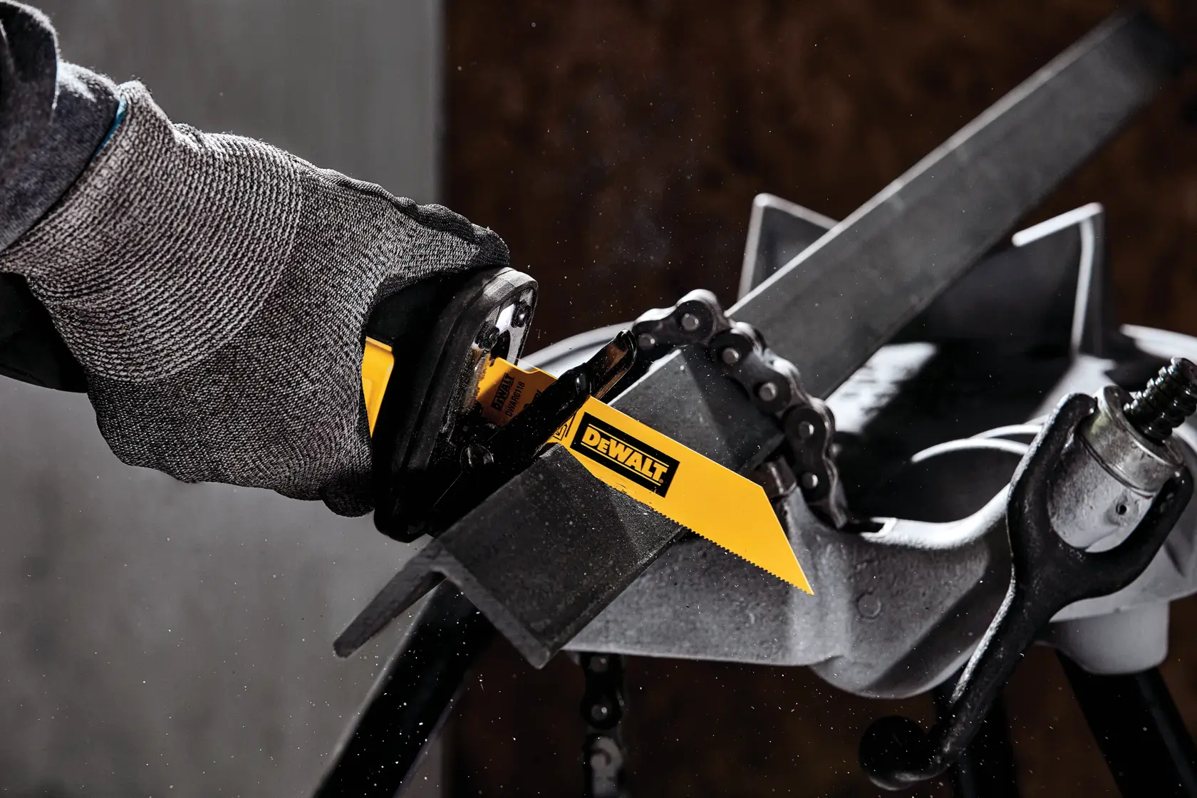 A close-up of a DEWALT reciprocating saw blade cutting through a metal bar, with a gloved hand holding the tool.
