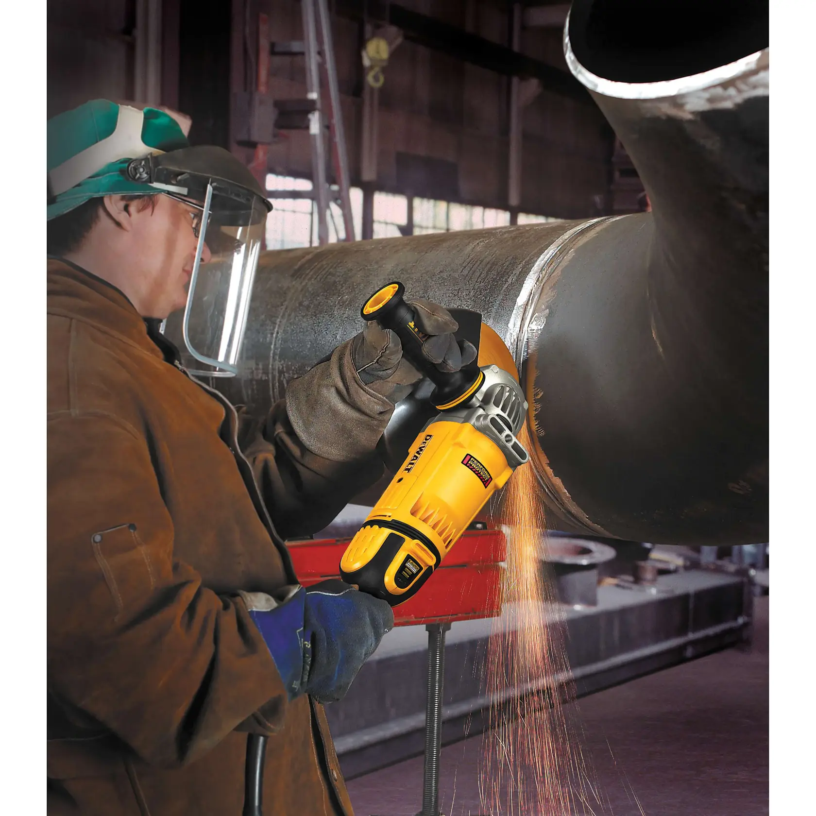 A worker wearing protective gear uses a DEWALT DWE4599N angle grinder to grind a large metal pipe, with sparks flying from the tool.
