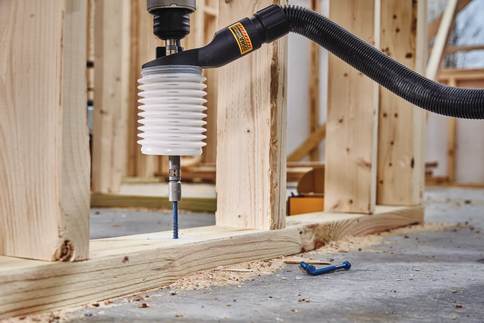 Dust extraction tube kit with hose drilling wooden surface.