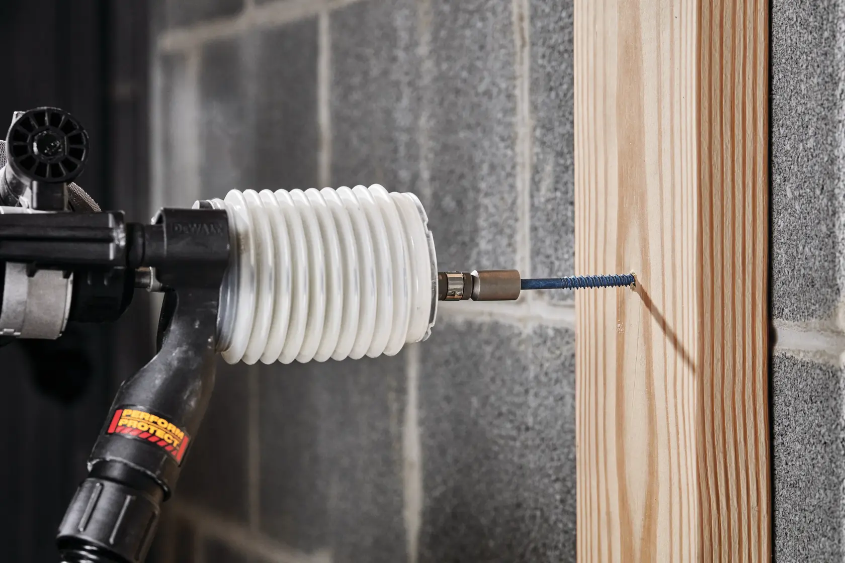 Close up of Dust extraction tube kit with hose drilling wooden plank.