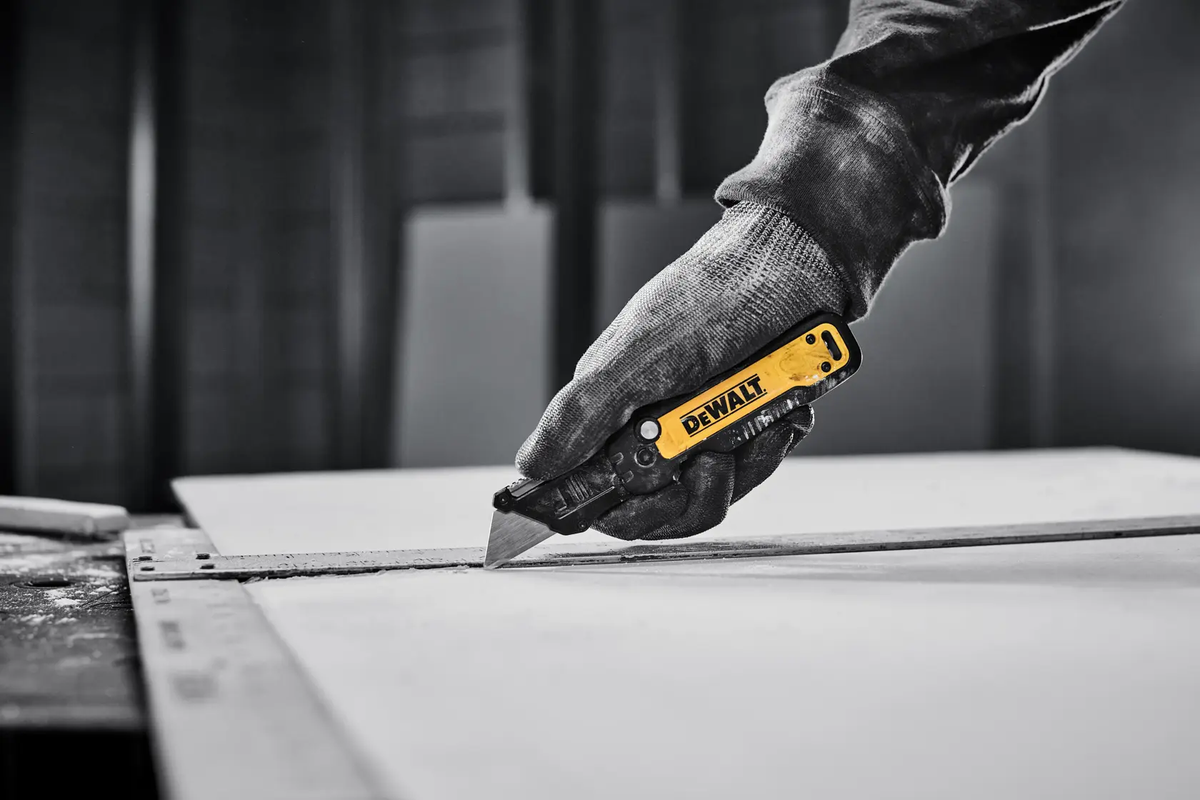 DEWALT knife cutting sheet of drywall with T-square as a guide