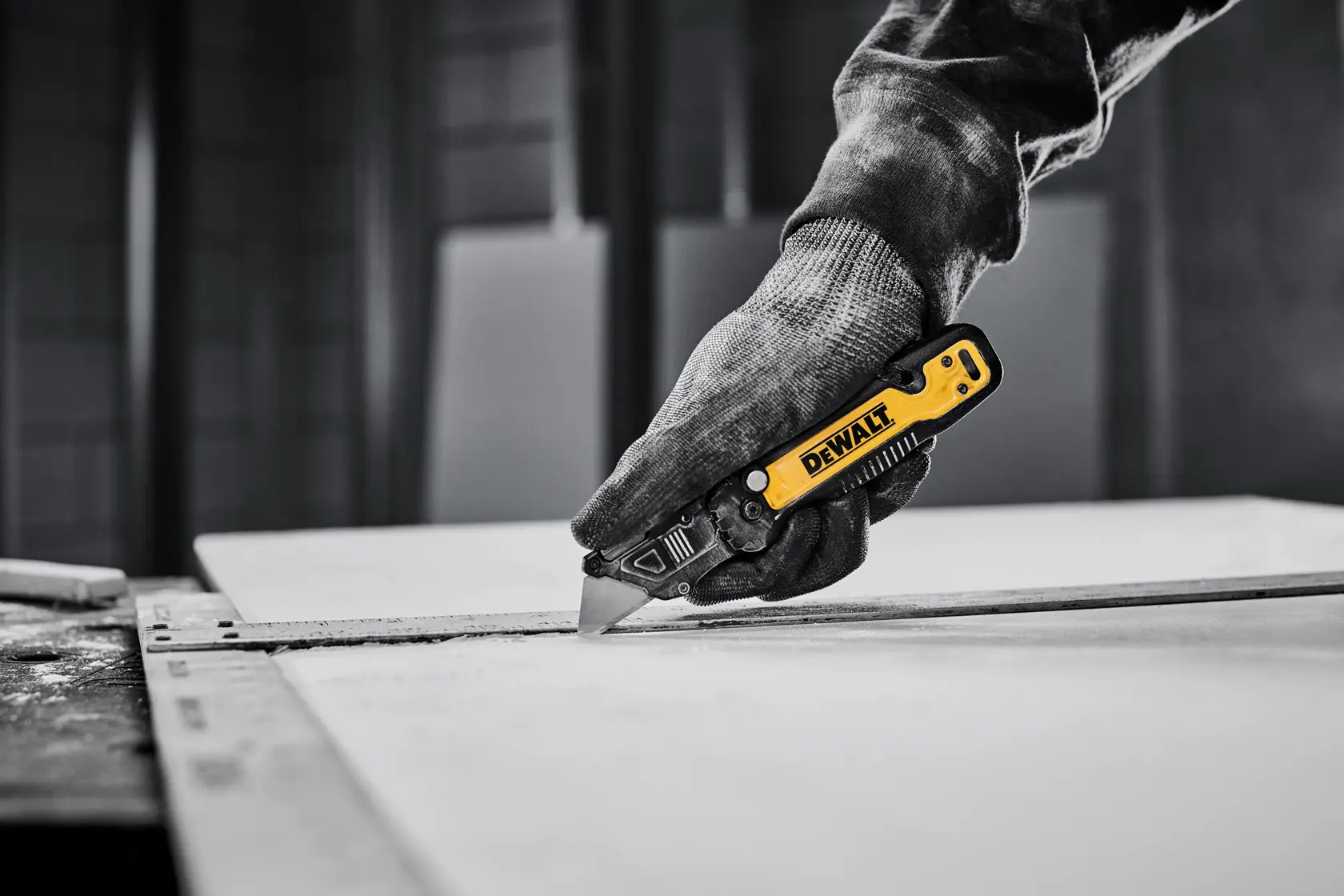 DEWALT knife cutting sheet of drywall with T-square as a guide
