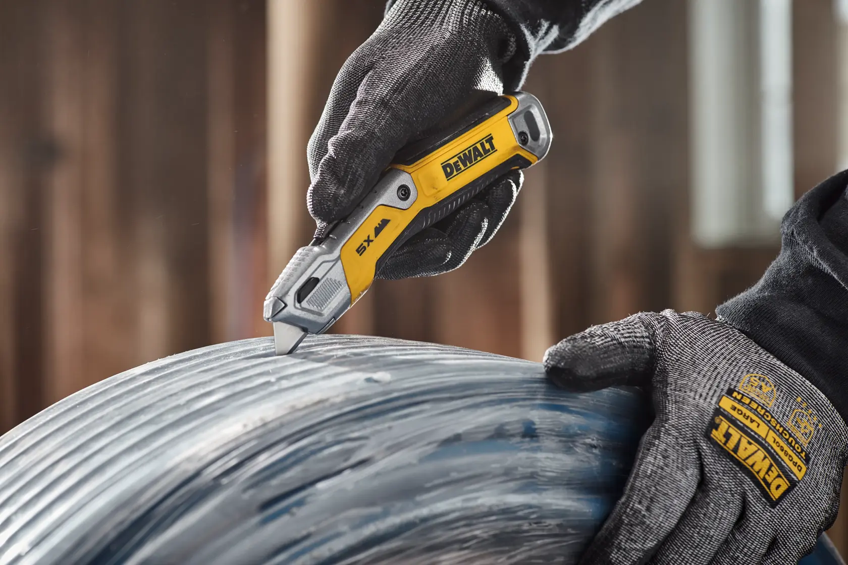 Worker cutting plastic wrap from PEX pipe packaging with DEWALT® DWHT10998 Utility Knife