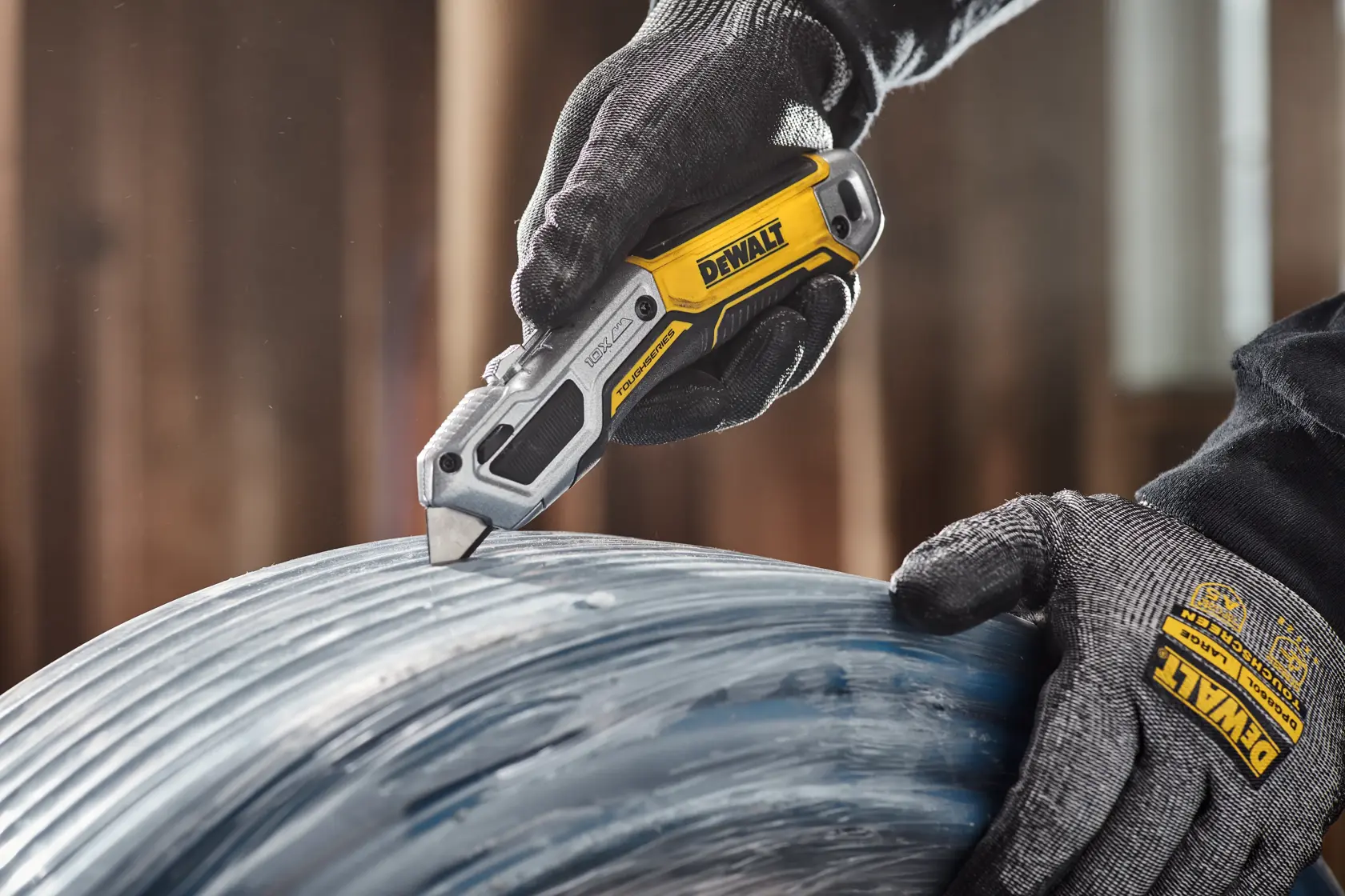 Worker cutting plastic wrap from PEX pipe packaging with DEWALT® TOUGHSERIES™ DWHT10999 Utility Knife