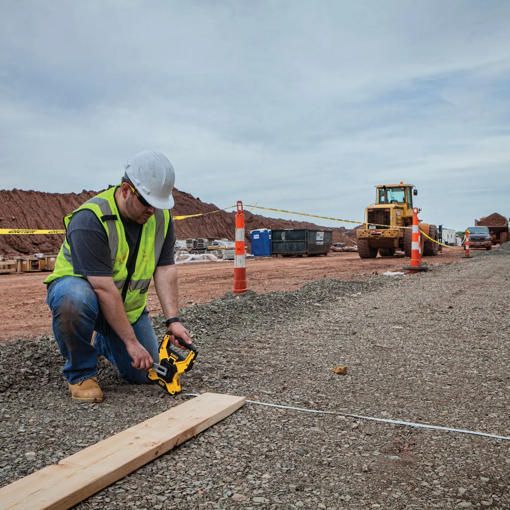 Gear mechanism of 100 feet Fiberglass Long Tape being used by worker to retract tape after measurement of concrete road.