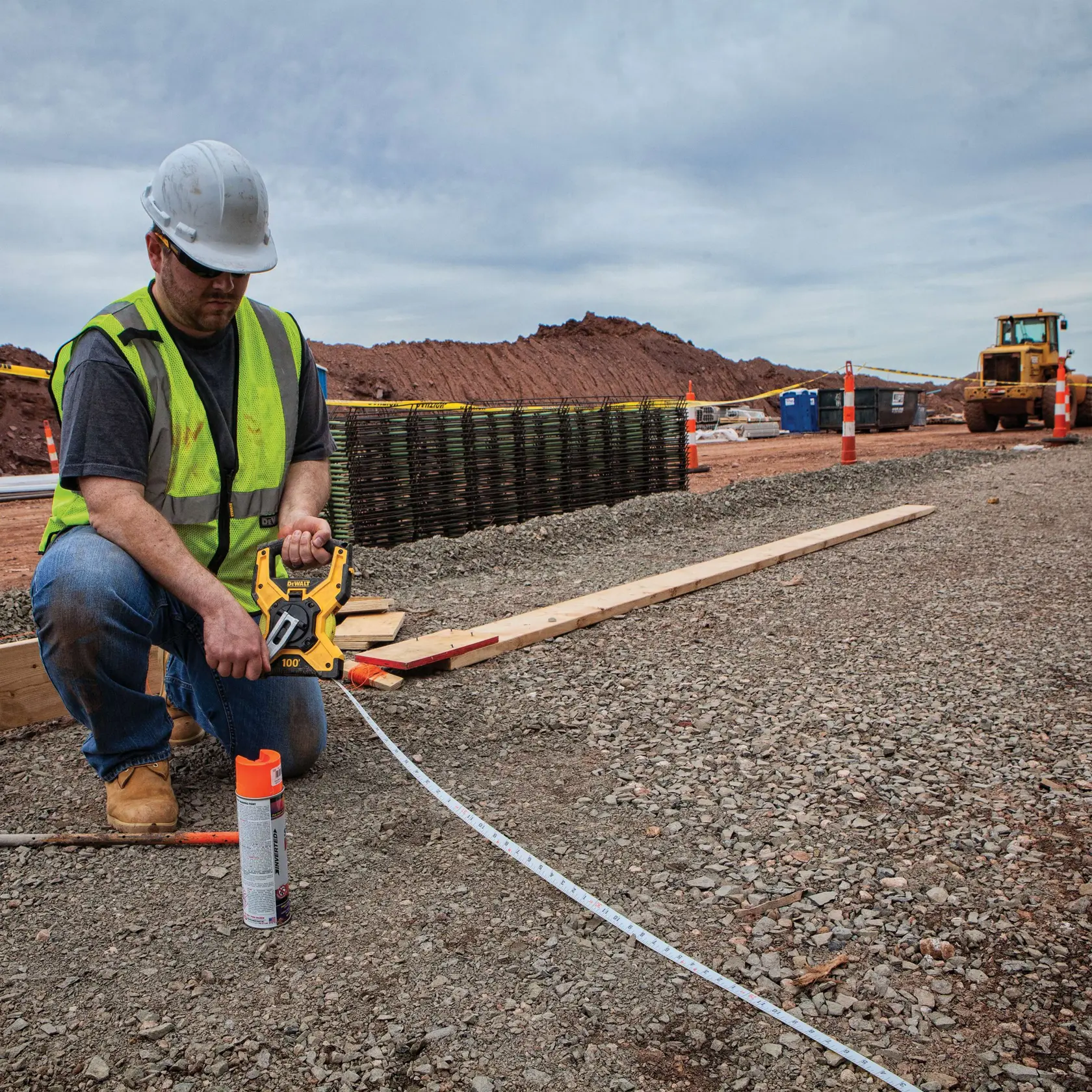 Gear mechanism of 100 feet Fiberglass Long Tape being used by worker to retract tape after measurement of concrete road.