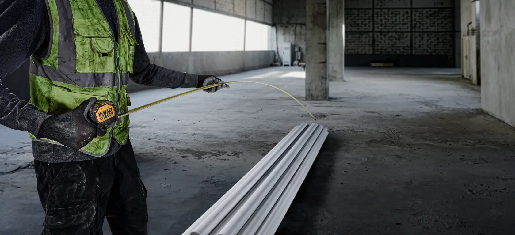 Tough Series 25 feet Tape Measure ready to be used by worker to measure length of PVC pipes at construction site.