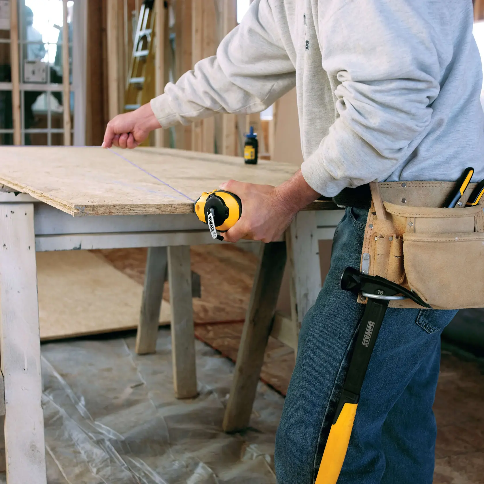 Reel Kit with Blue Chalk being used by worker to mark line on wooden surface