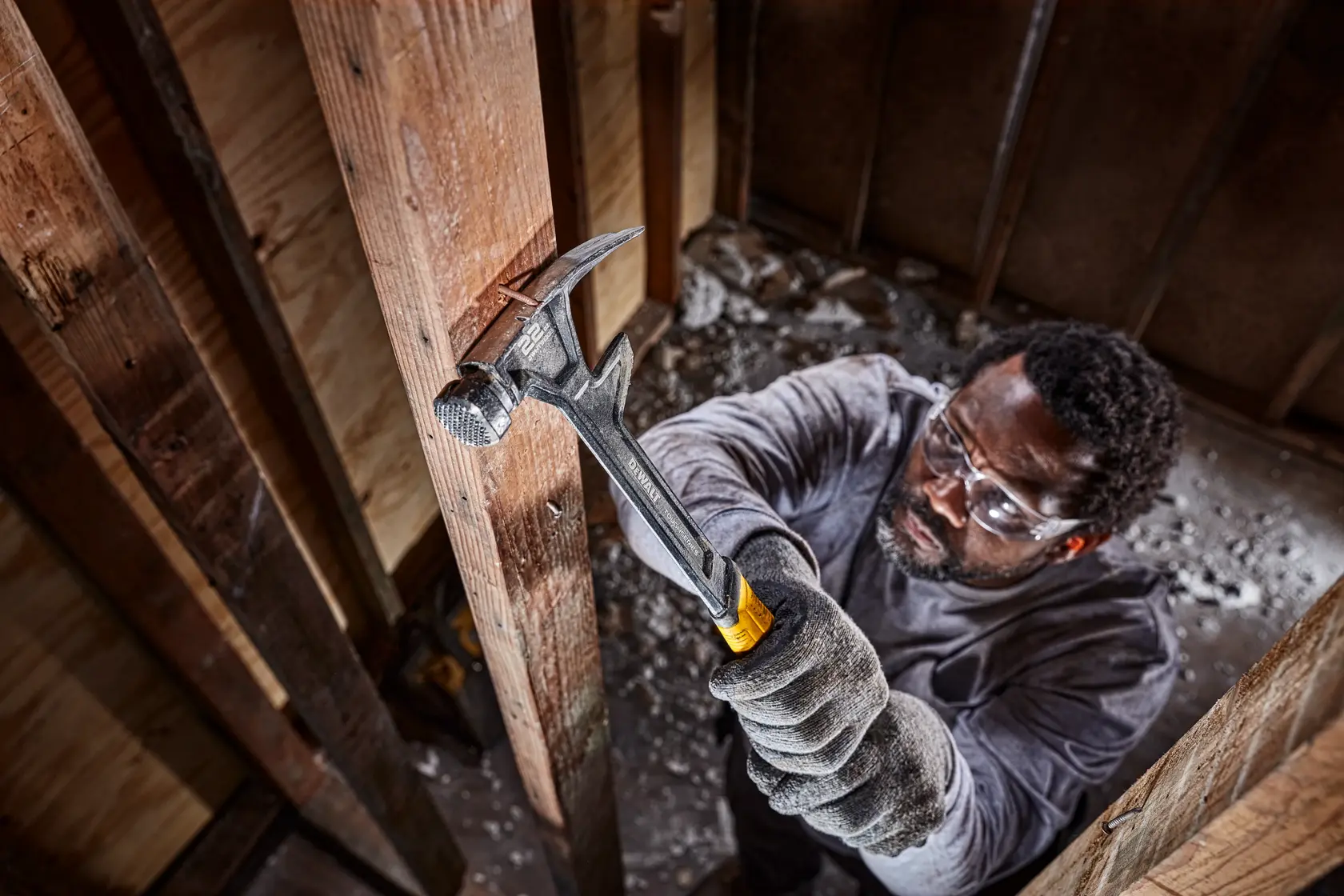22 ounce demolition hammer being used to remove a nail from a wood column by a person.