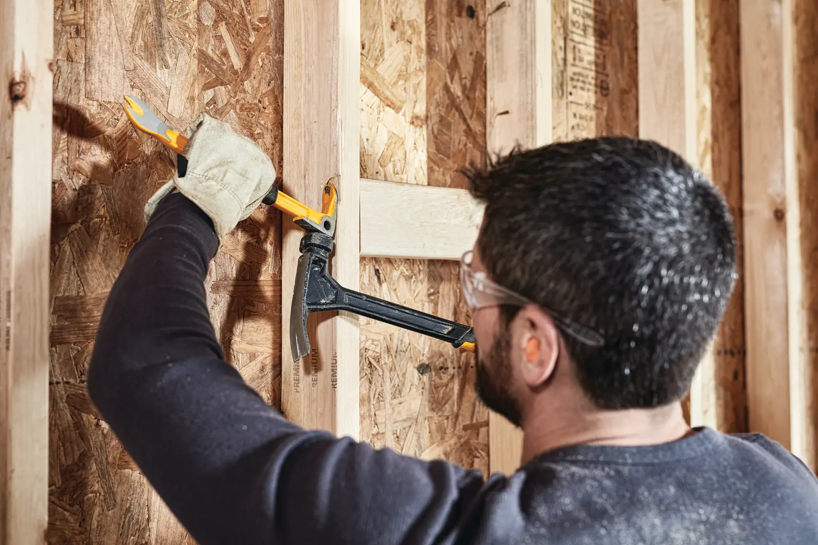 9 inch Precision Claw Bar being used with hammer by a person to pull nail from wood.