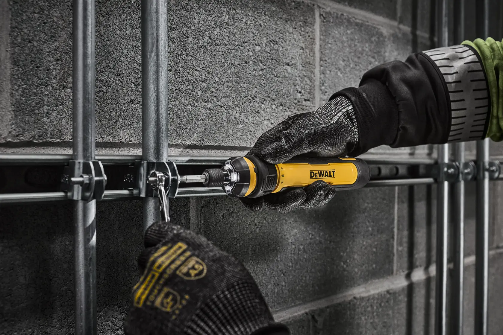 Worker tightening electrical conduit clamps on a commercial jobsite with DEWALT 4V USB Screwdriver