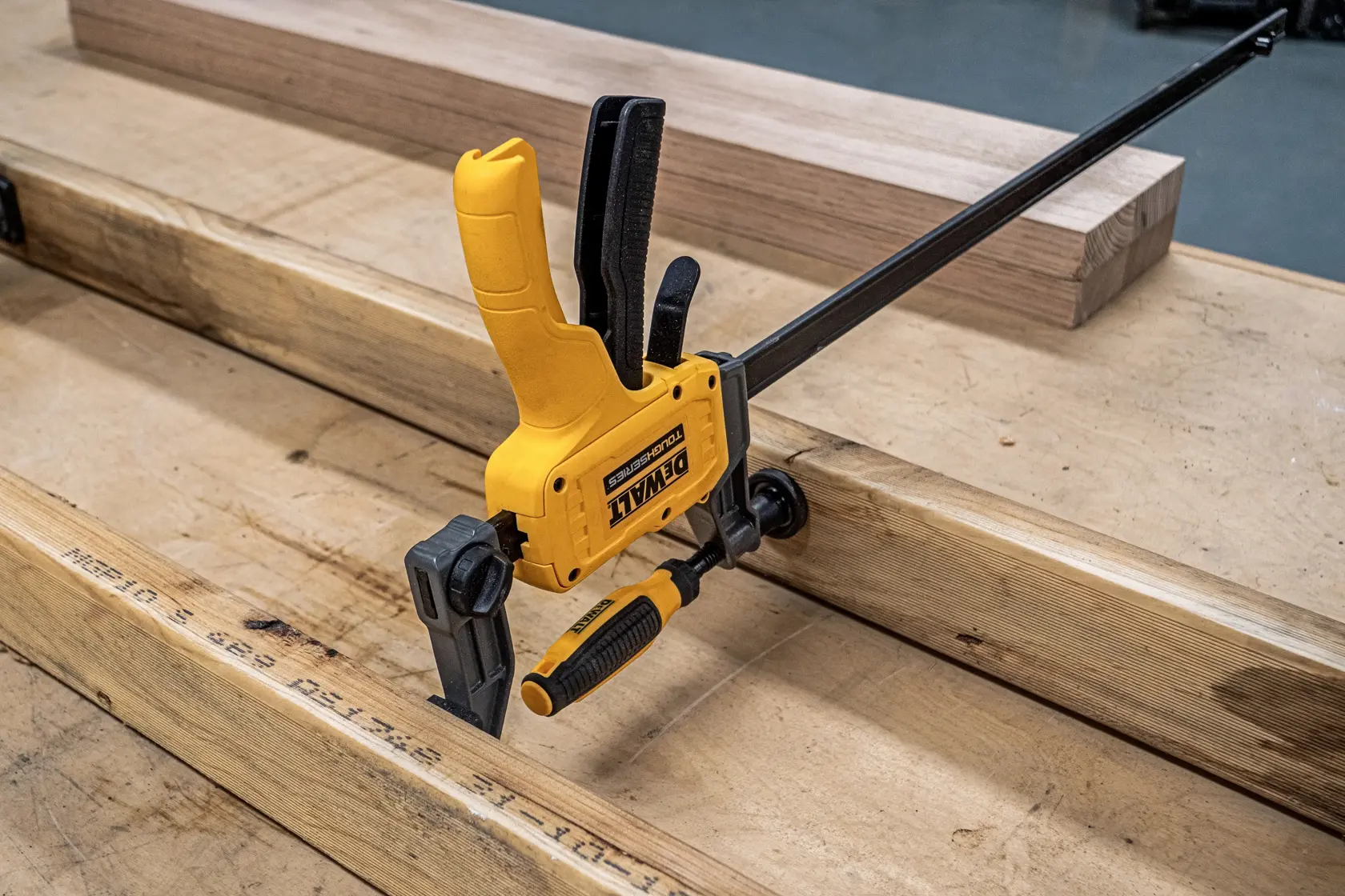 DEWALT 24“ Hybrid Clamp spreading apart two pieces of wood on work surface