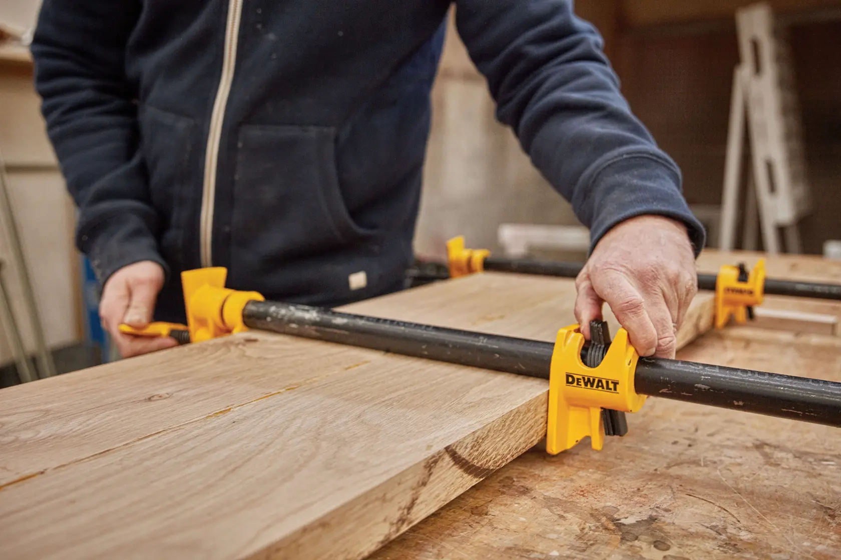 Close up of  three quarter inch Pipe Clamp Fixture being used on a wooden structure by a person.
