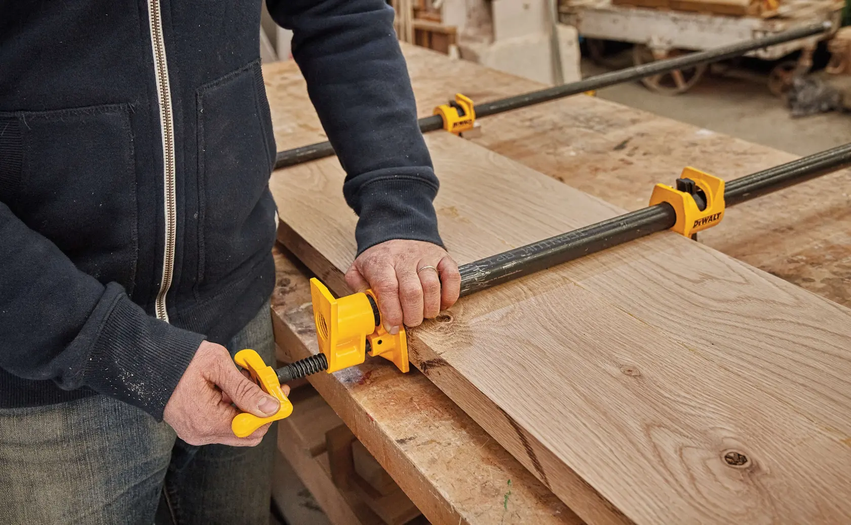 Three quarter inch Pipe Clamp Fixture being used on a wooden structure by a person.